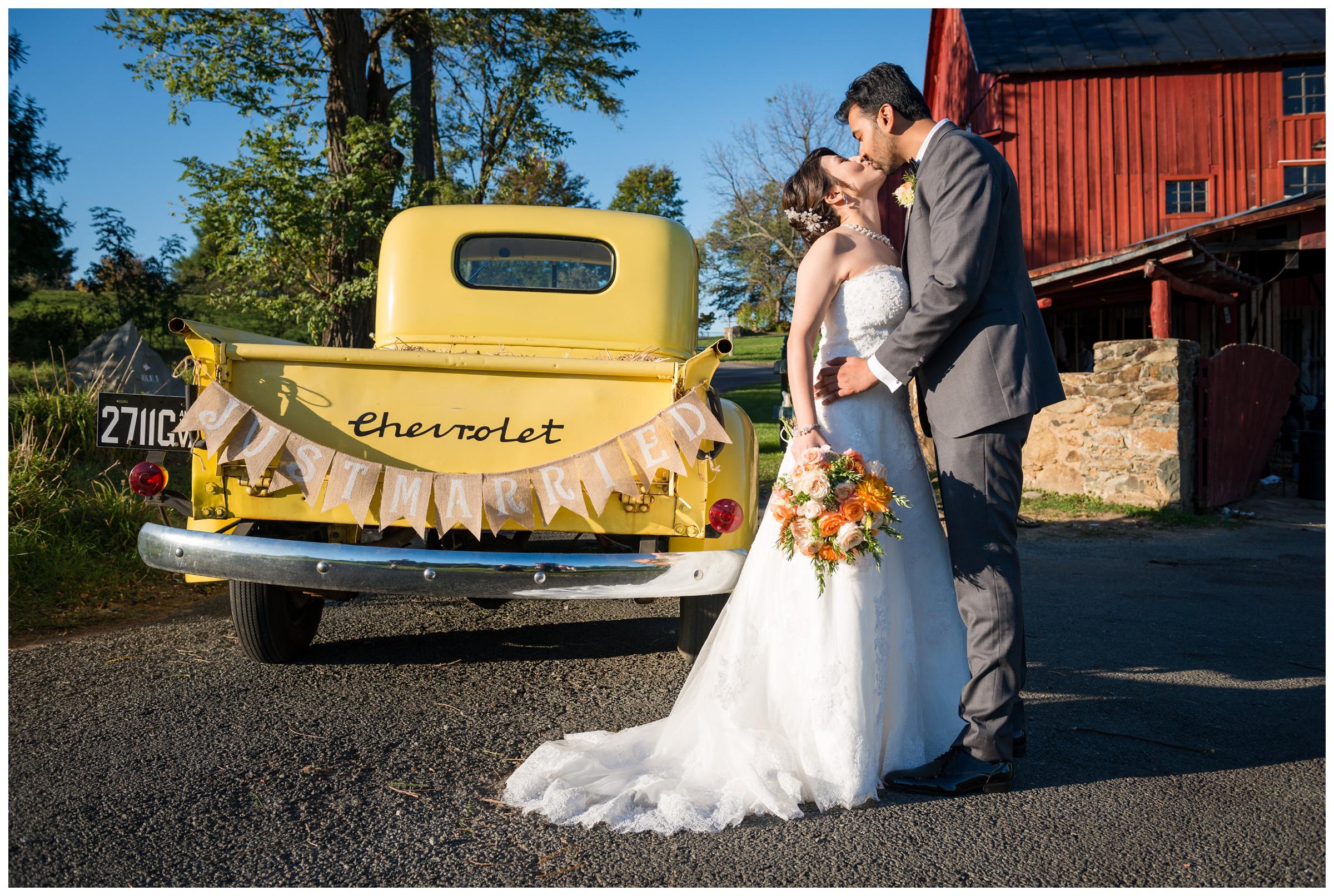 Bride and groom with vintage yellow Chevrolet truck with "just married" banner