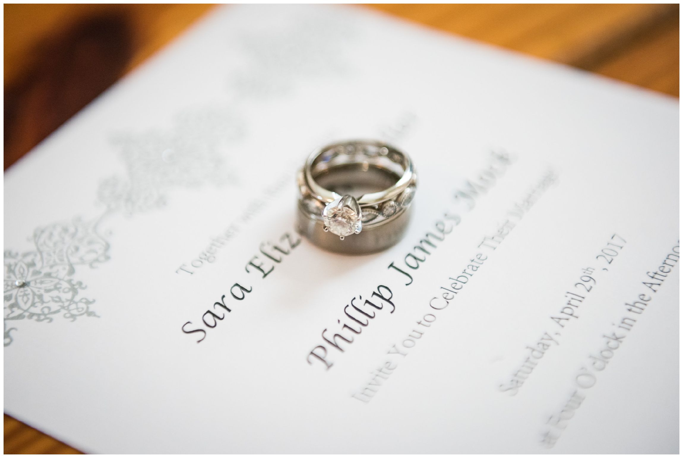wedding rings stacked on wedding invitation