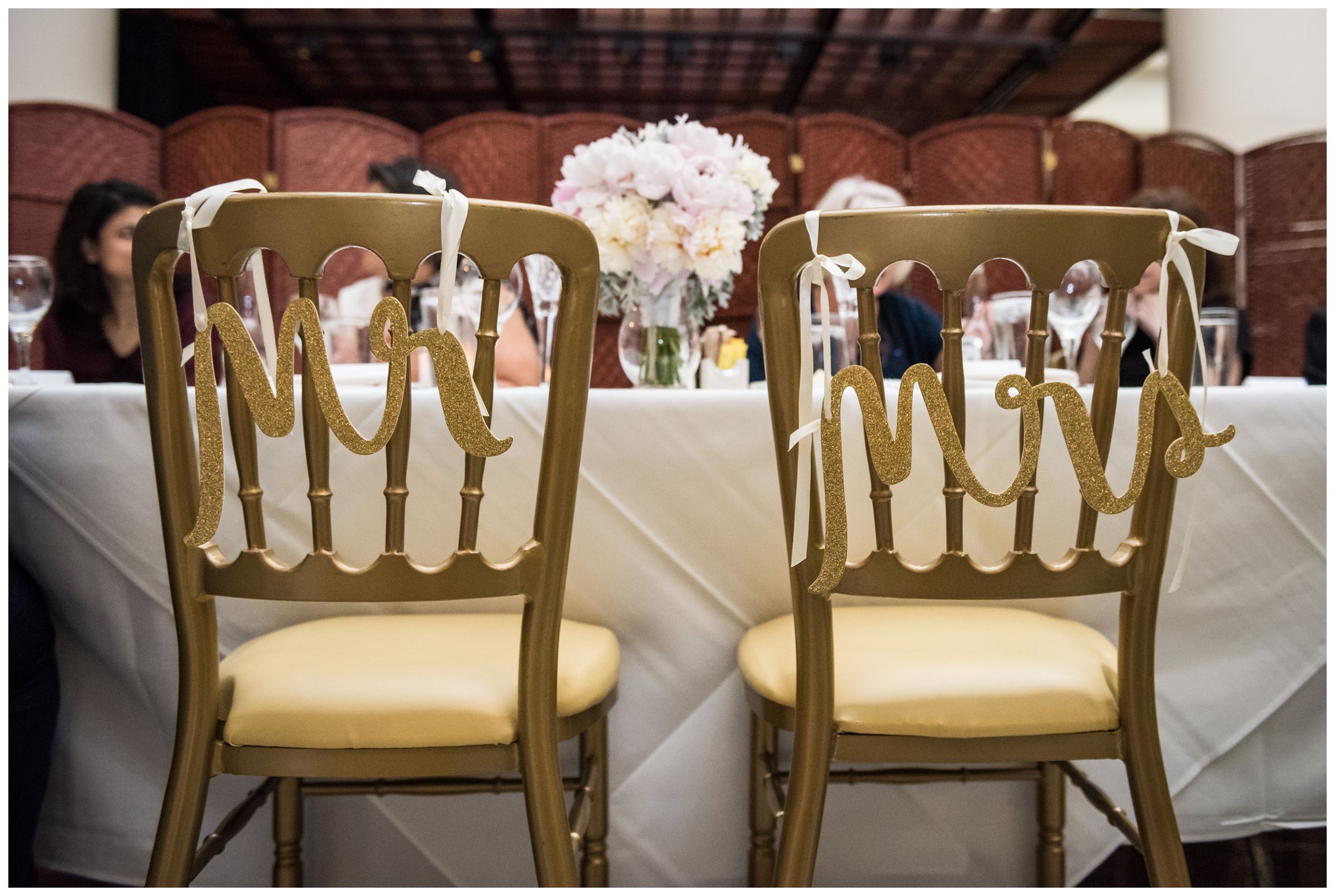 Mr. and Mrs. signs on bride and groom's chairs during intimate wedding reception dinner at Old Ebbitt Grill in Washington, D.C.