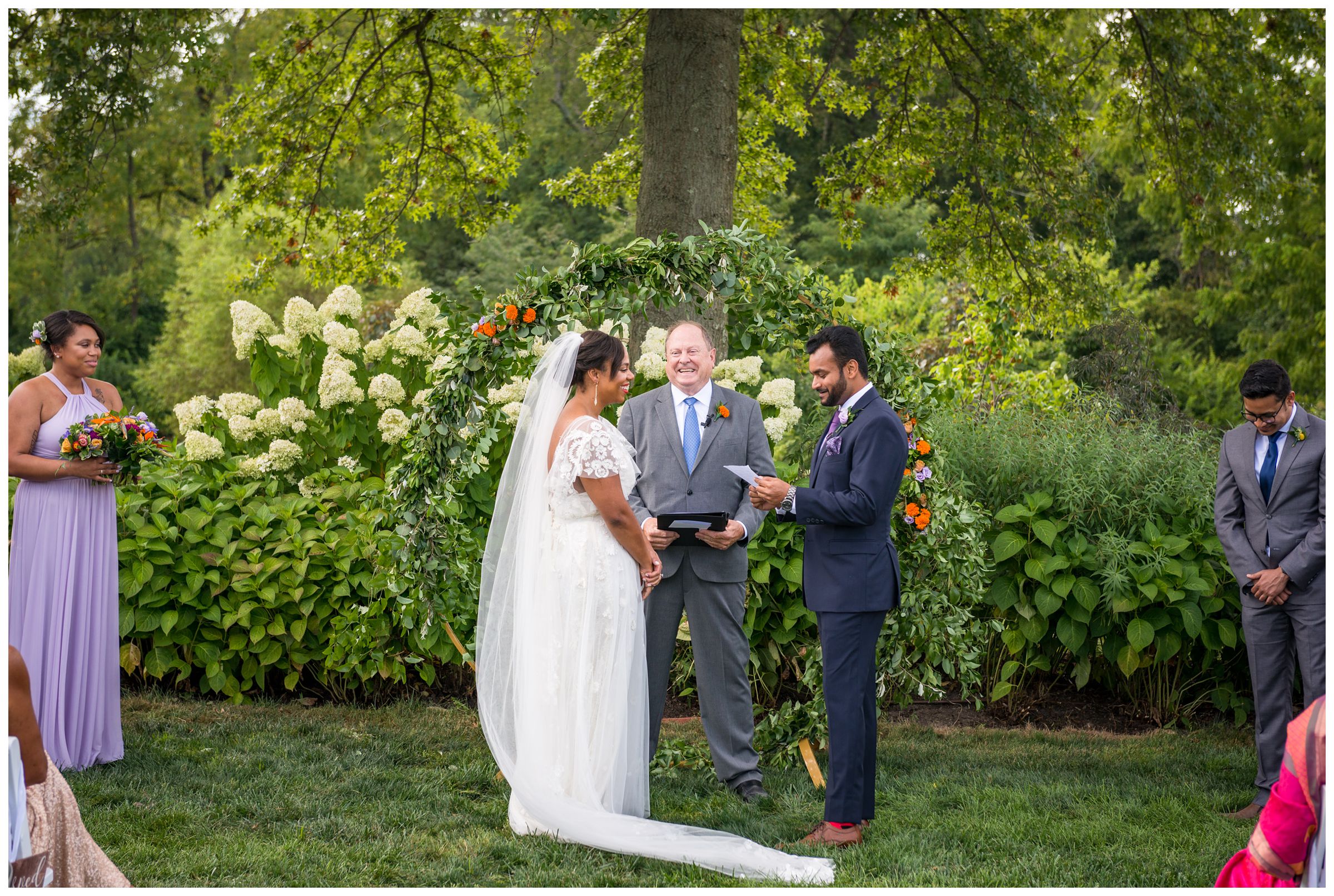 groom reading vows during wedding ceremony in front of floral moongate arch at Jorgensen Farms flower field