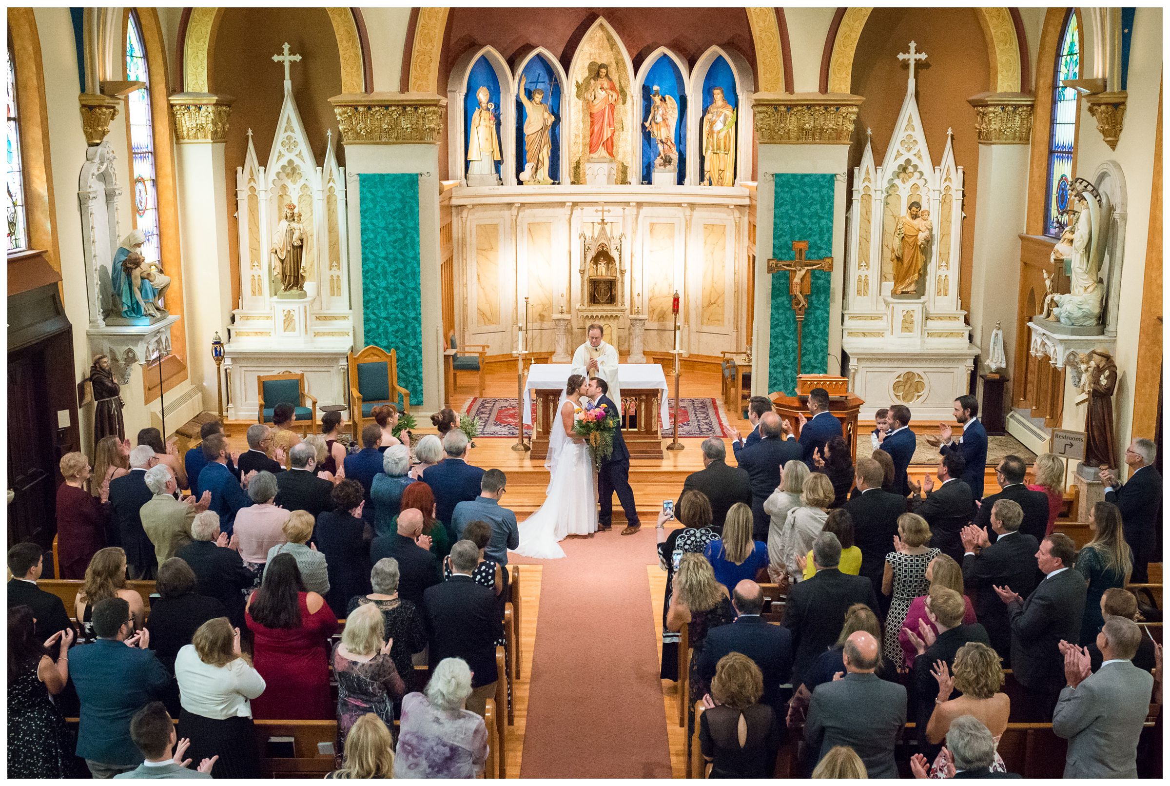 first kiss from balcony during indoor wedding ceremony at St. John the Baptist Catholic Church in the Short North in Columbus, Ohio