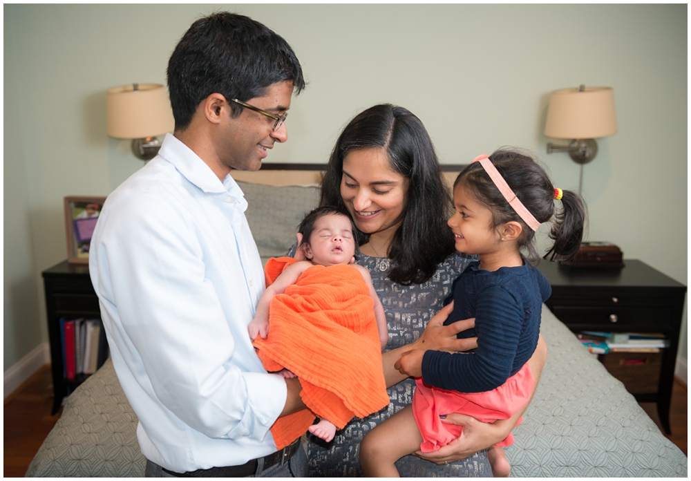 parents and sister with newborn baby girl in home