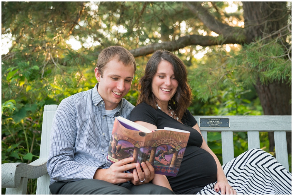 pregnant couple reading Harry Potter book on park bench