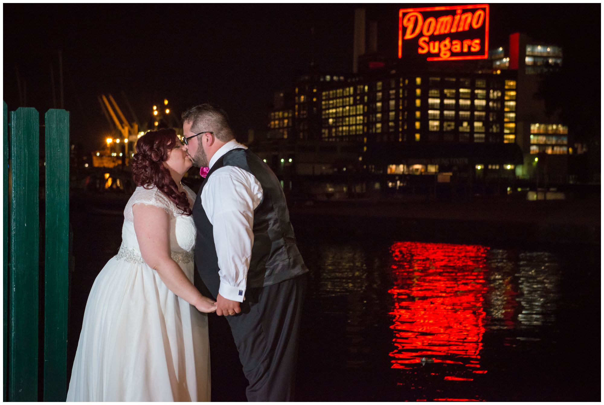 Bride and groom at nighttime in front of Domino Sugar factory in Baltimore