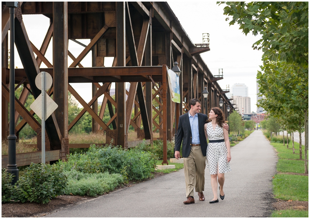 engaged couple walking by railroad bridge