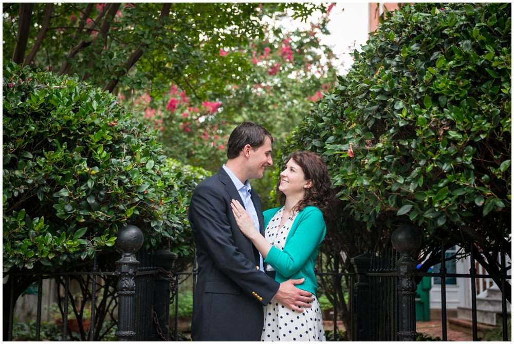 engaged couple near fence and shrubs