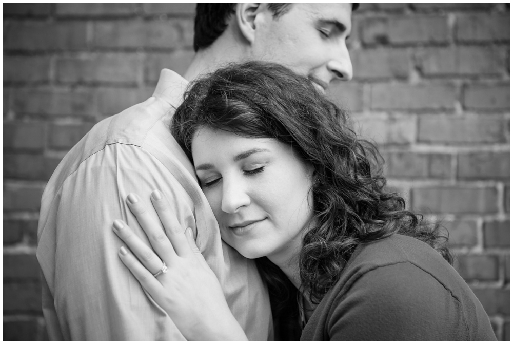 engaged couple embracing with brick background