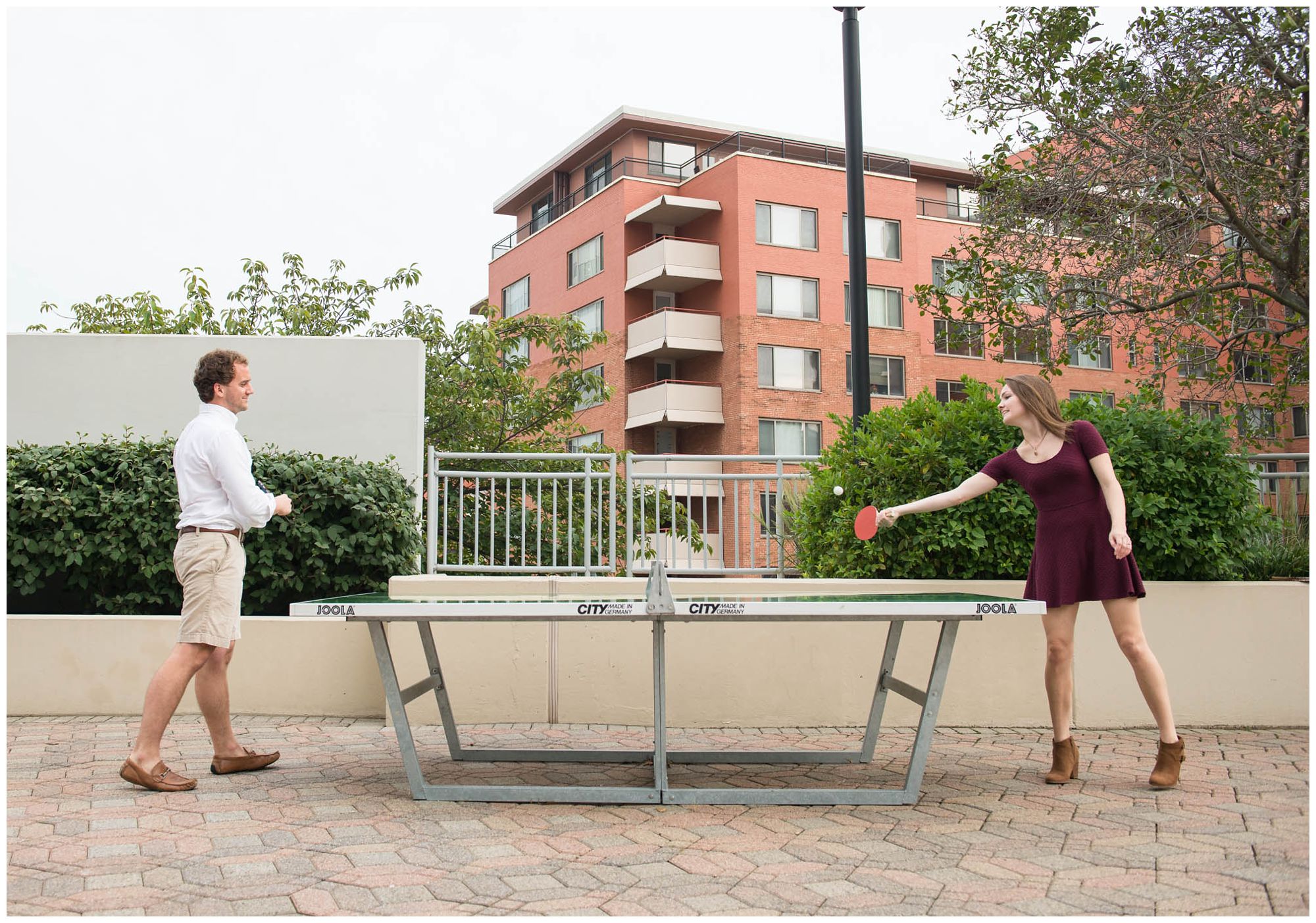 engaged couple playing ping pong in urban park