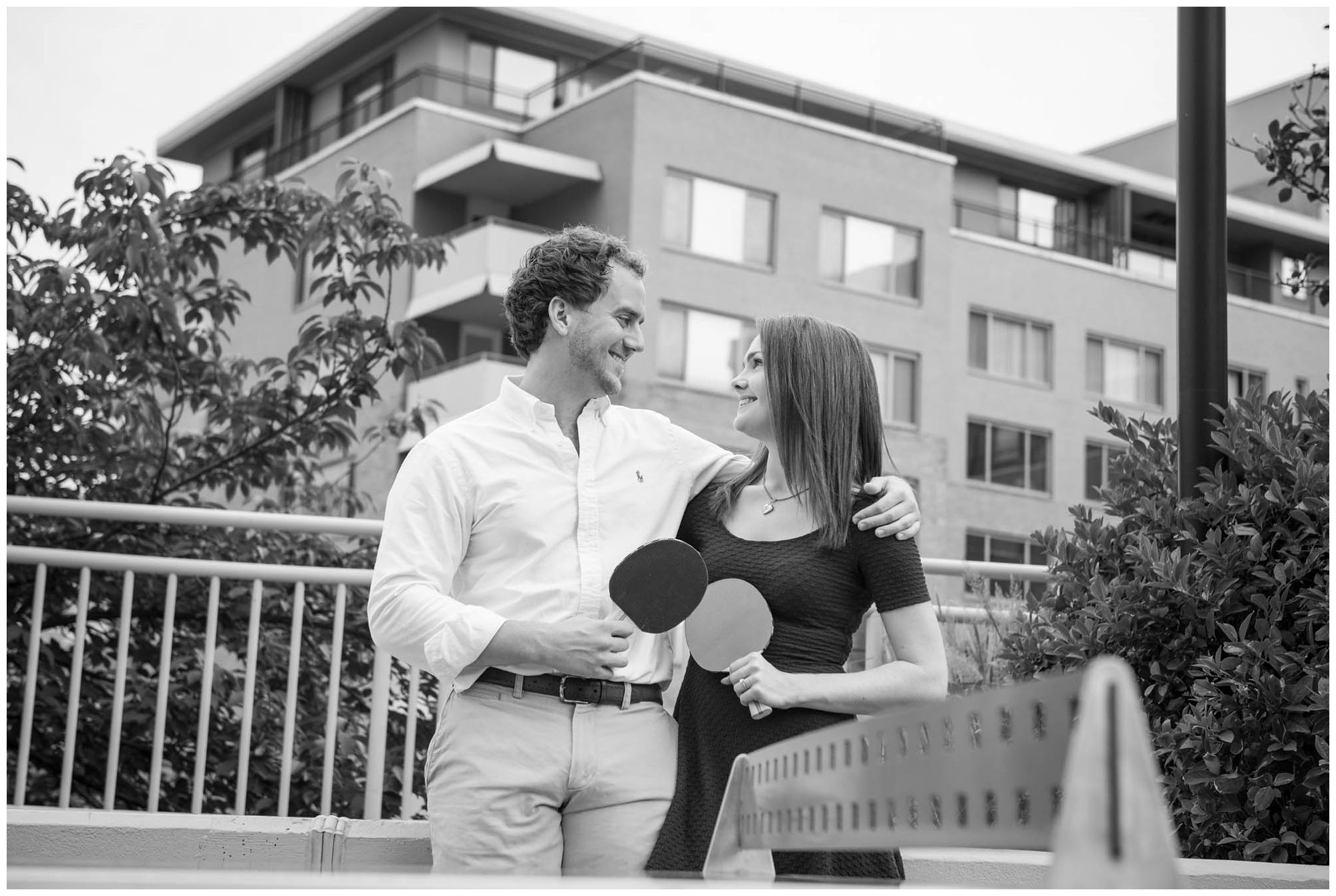 engaged couple playing ping pong in urban park