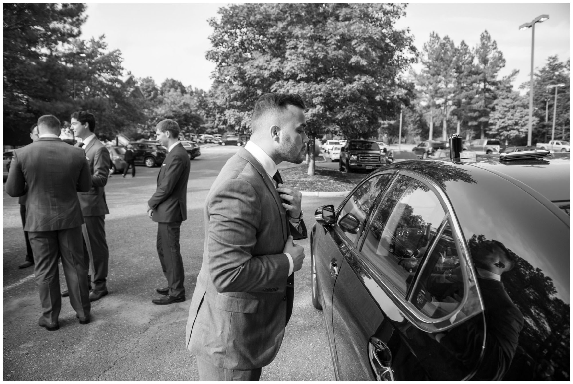 groomsmen tying ties in parking lot