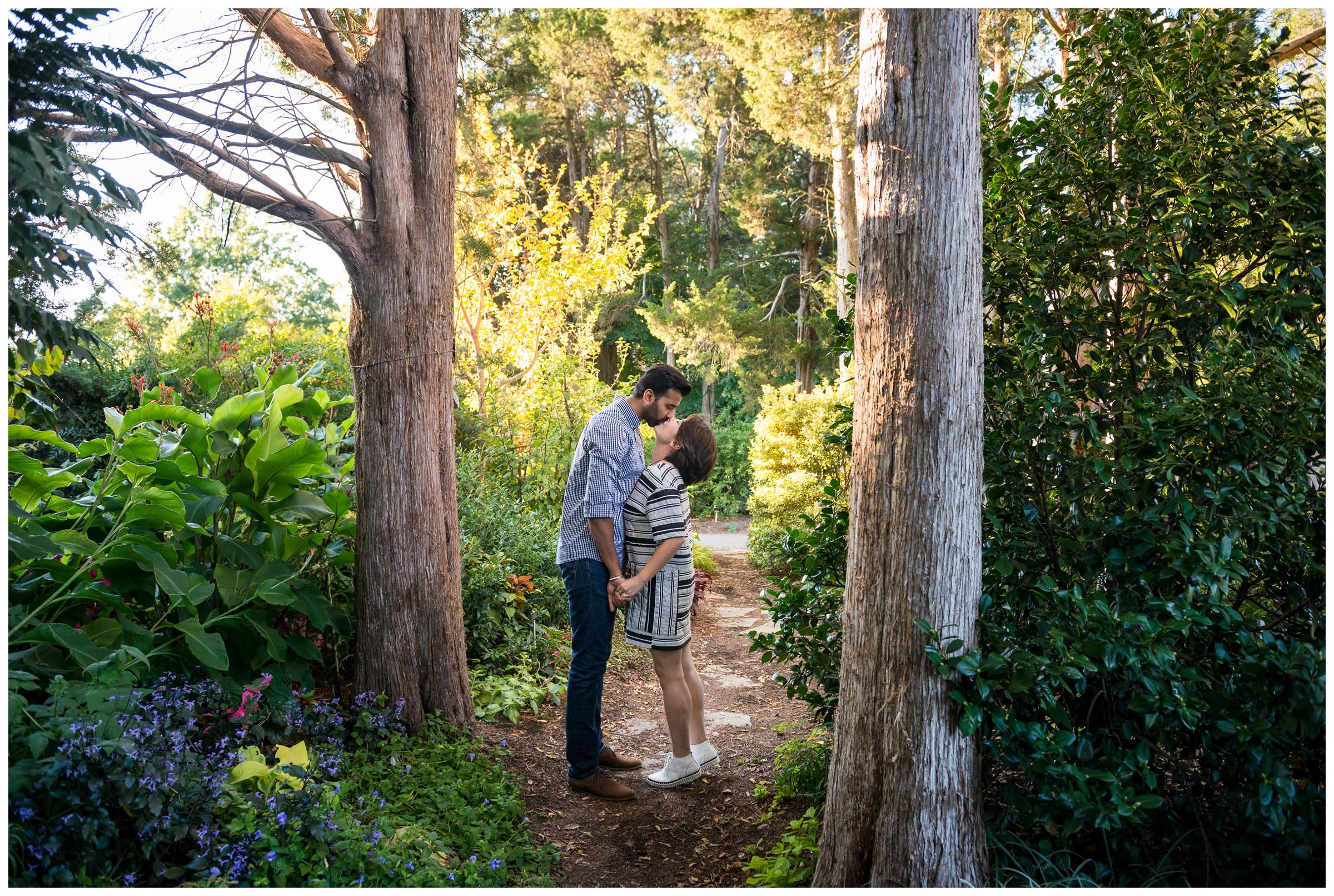 engaged couple kissing in forest 