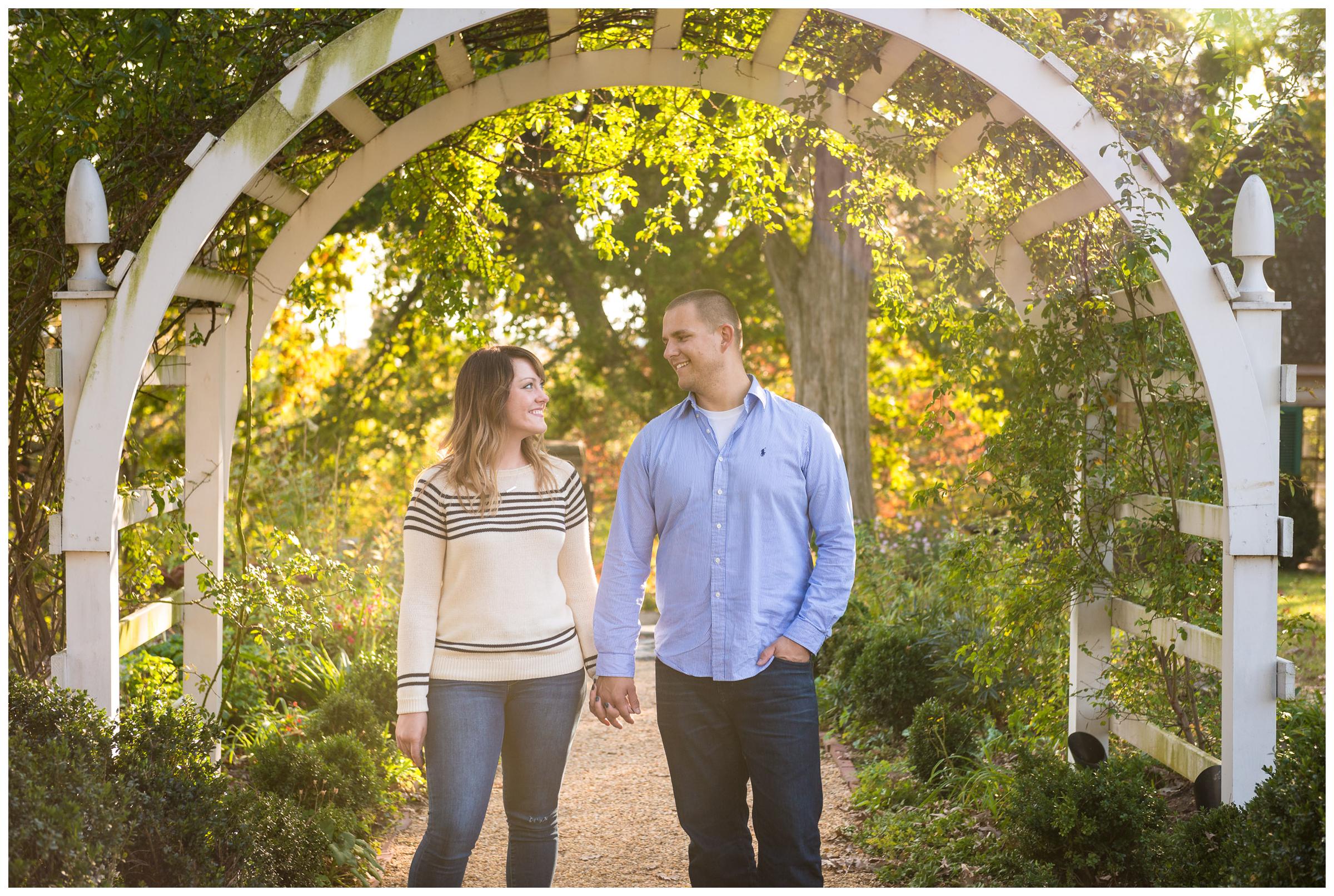 engaged couple under archway with sun flare