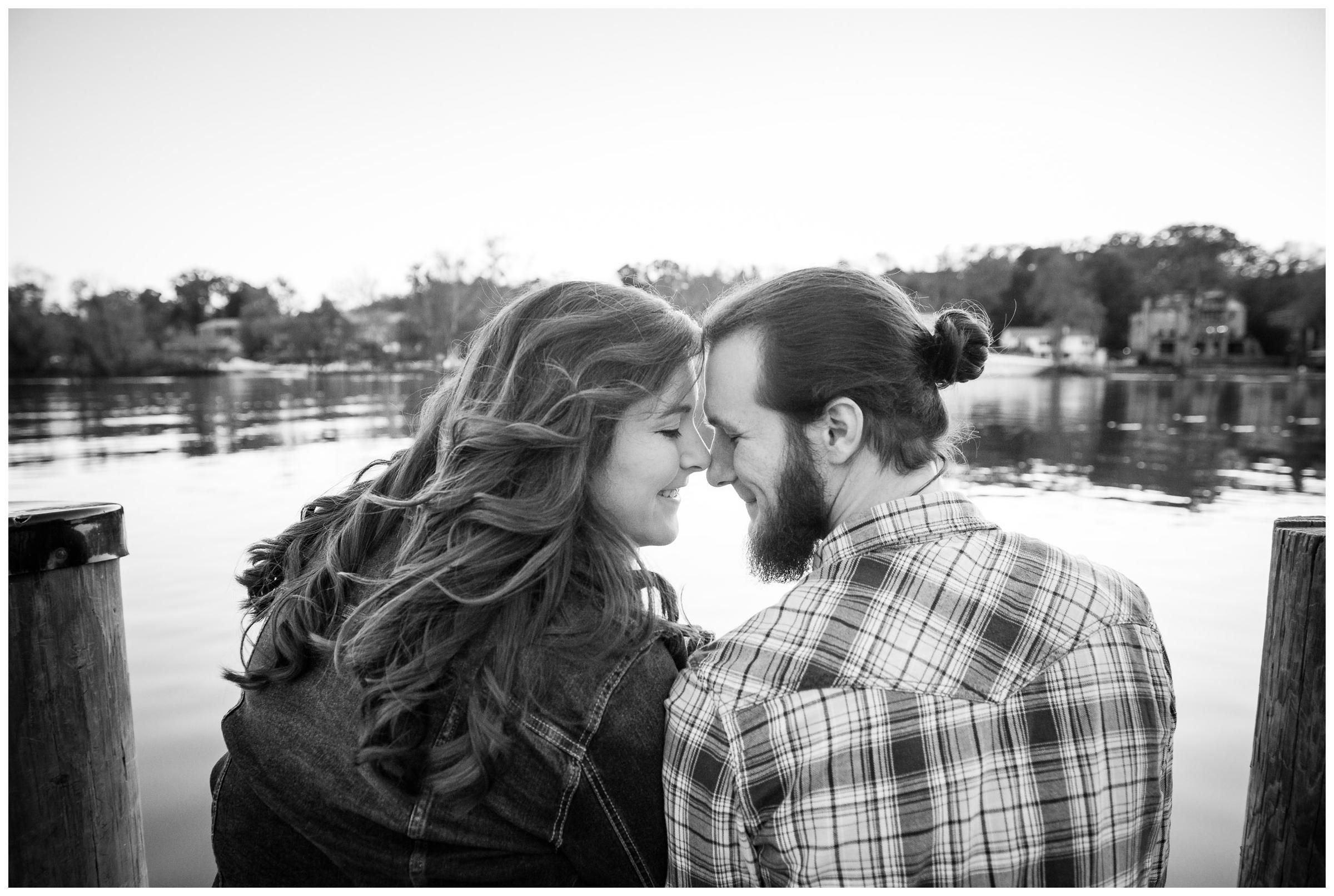 engaged couple sitting on dock by river