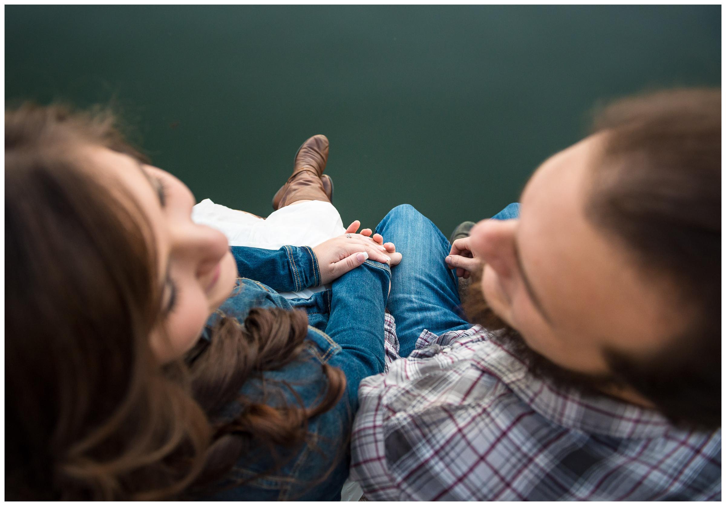 engaged couple sitting on dock by river