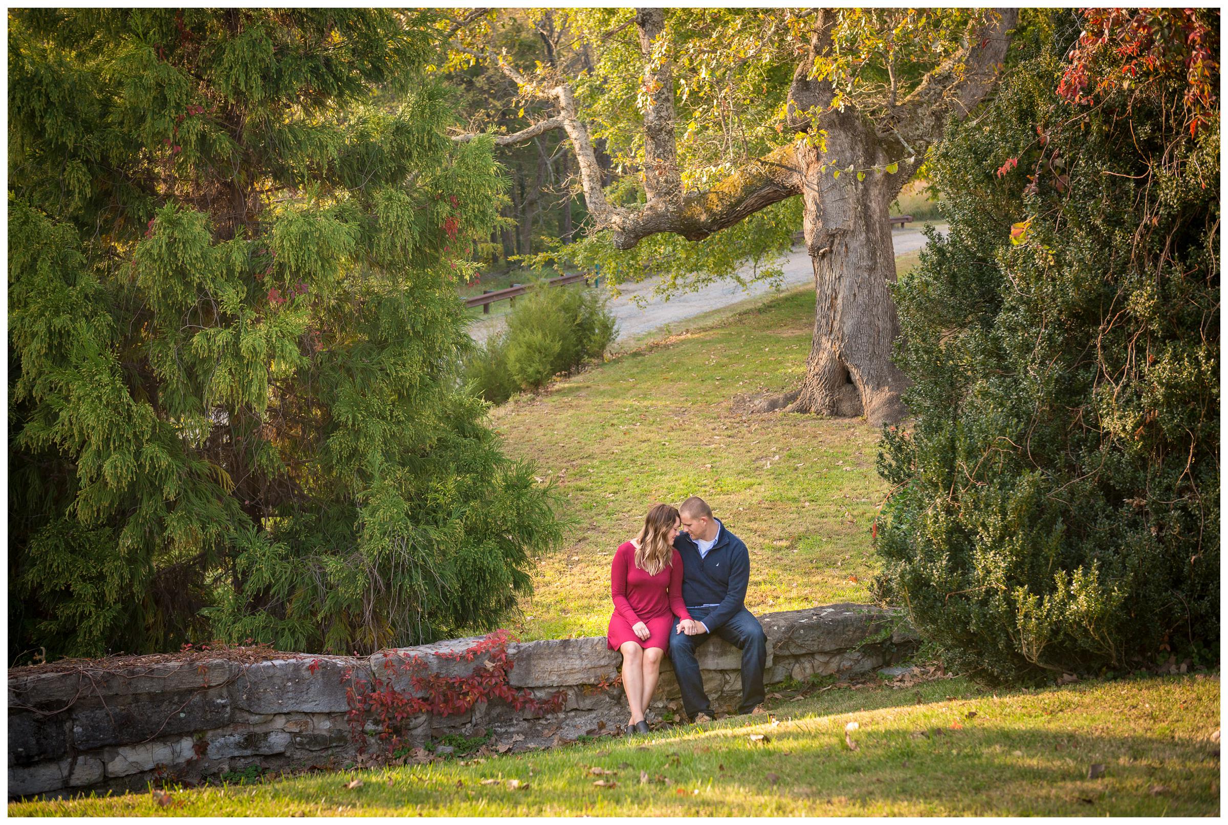 engaged couple sitting on stone wall