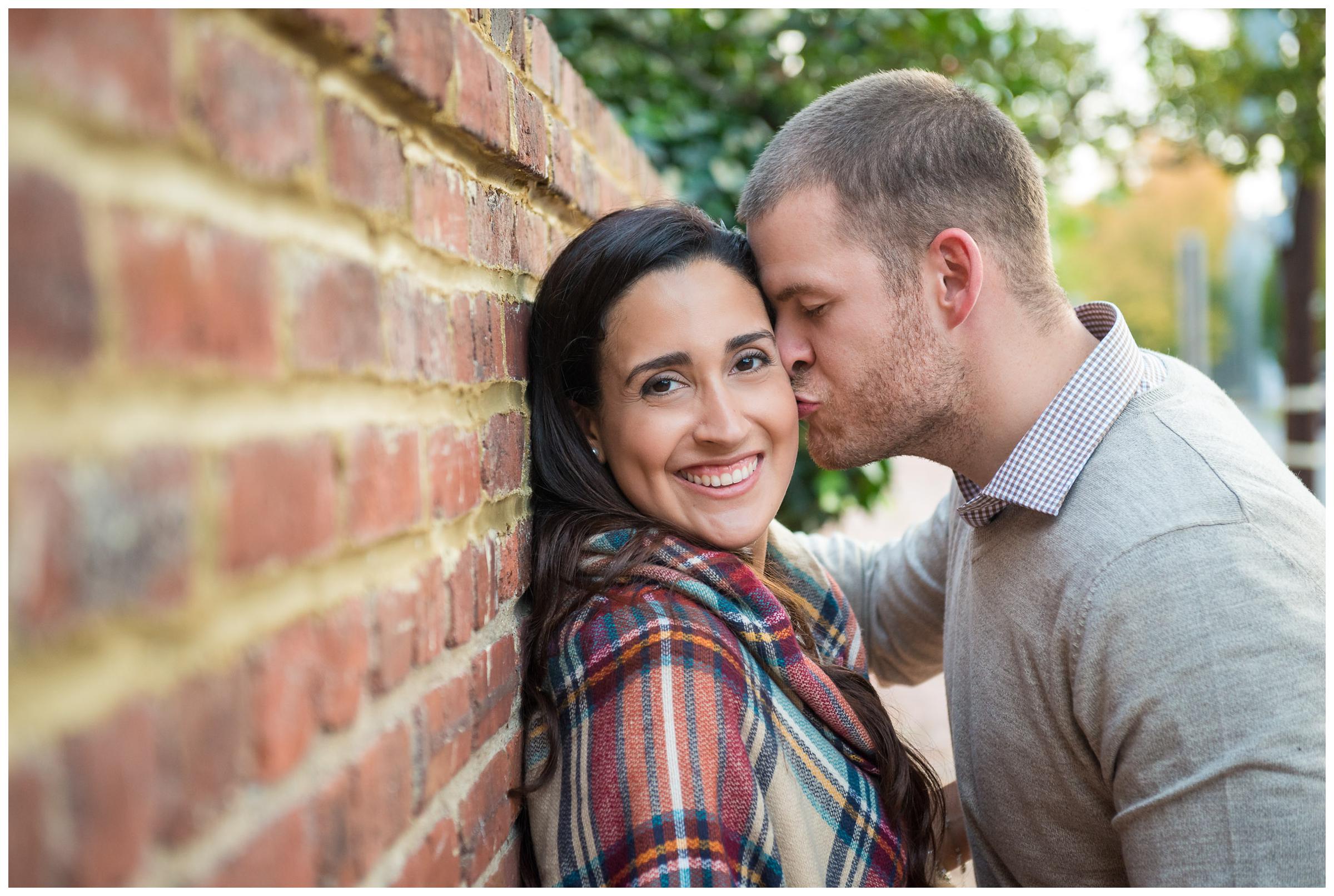 engaged couple along brick wall