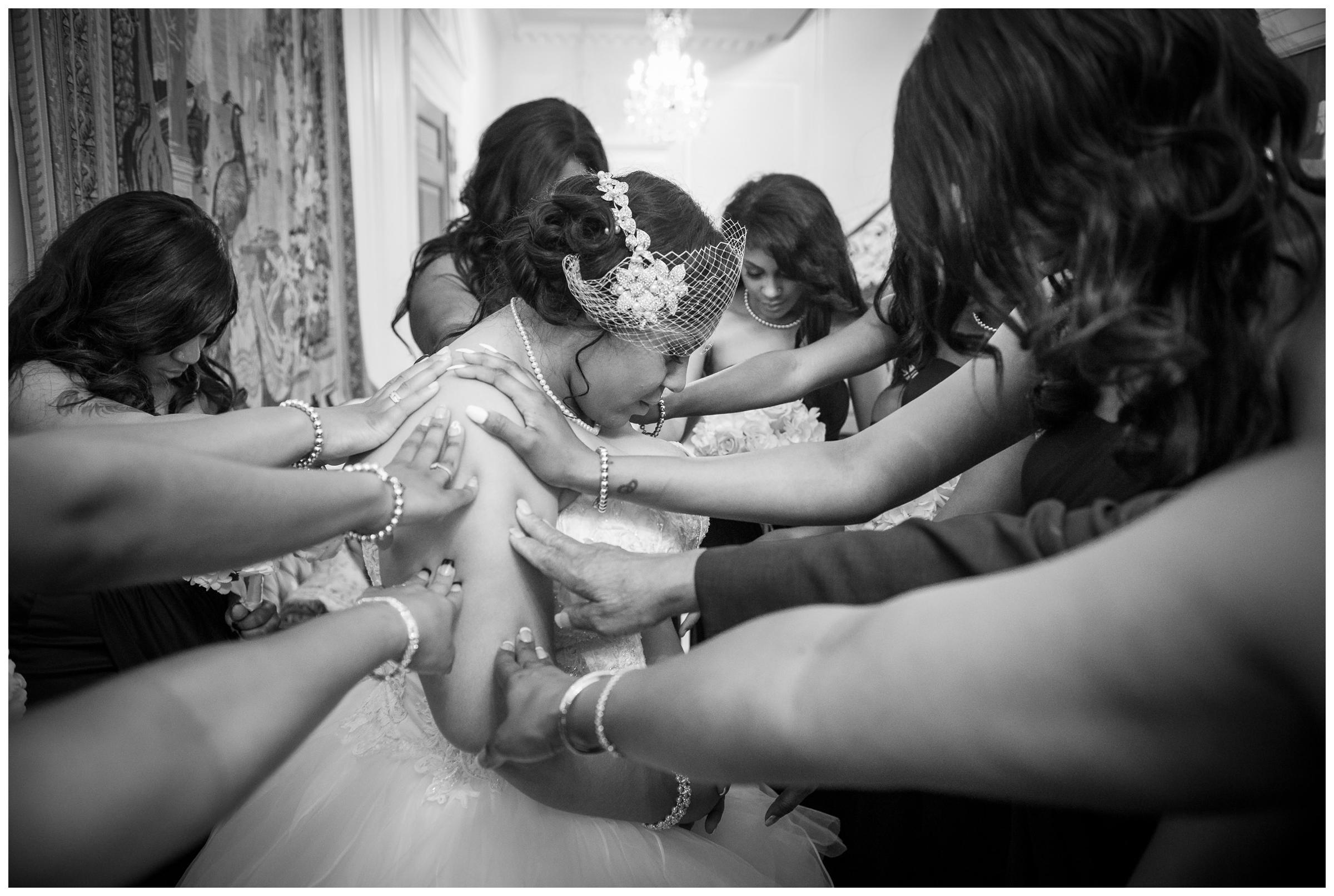 bridesmaids praying around bride before wedding