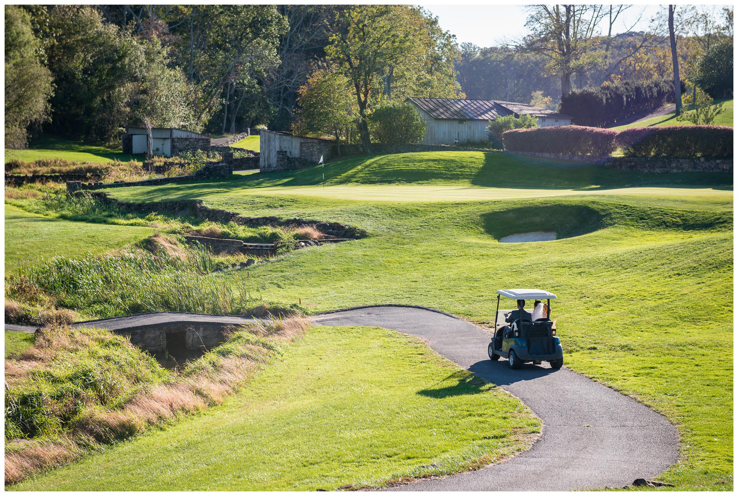 bride and groom ride in golf cart across green