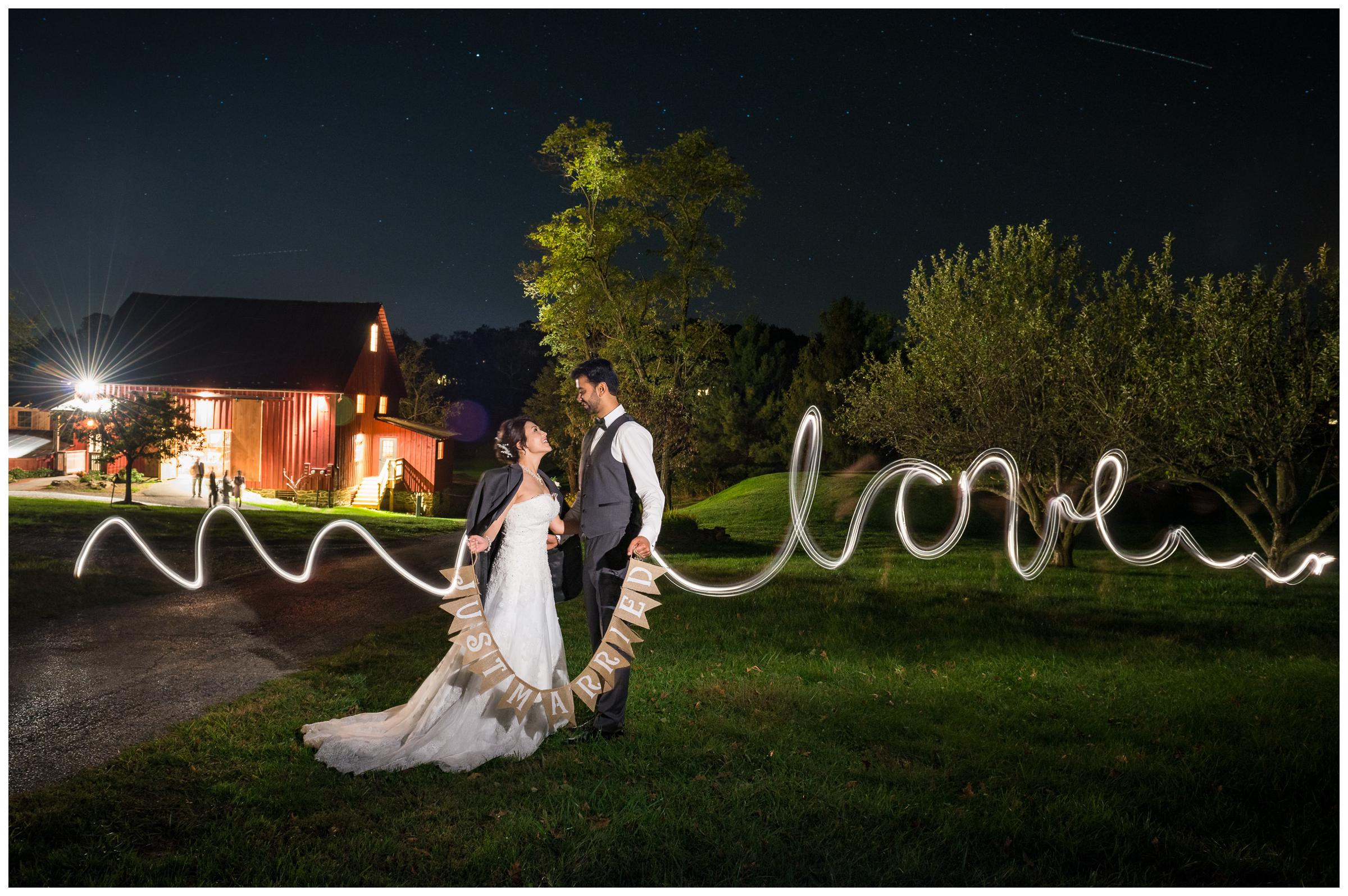 nighttime light painting spelling LOVE with bride and groom