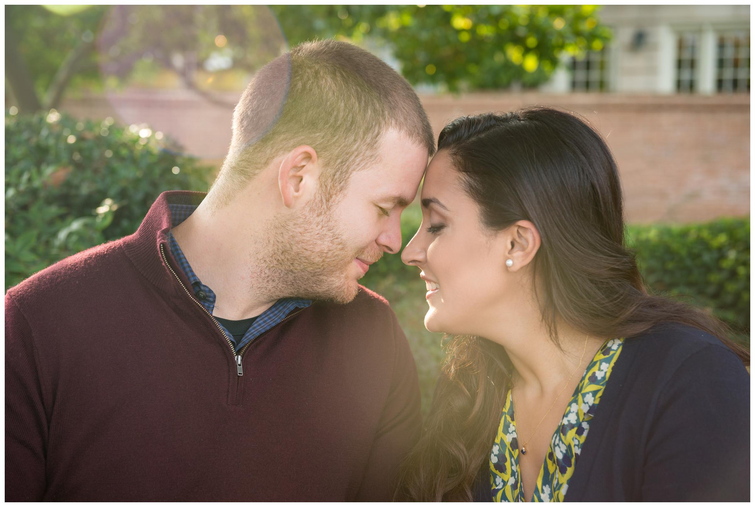 engaged couple snuggling with sun shining