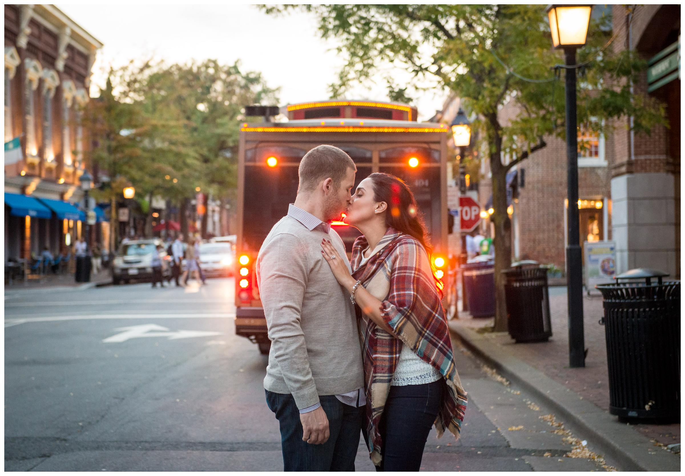 engaged couple kissing in front of historic trolley in Alexandria, Virginia