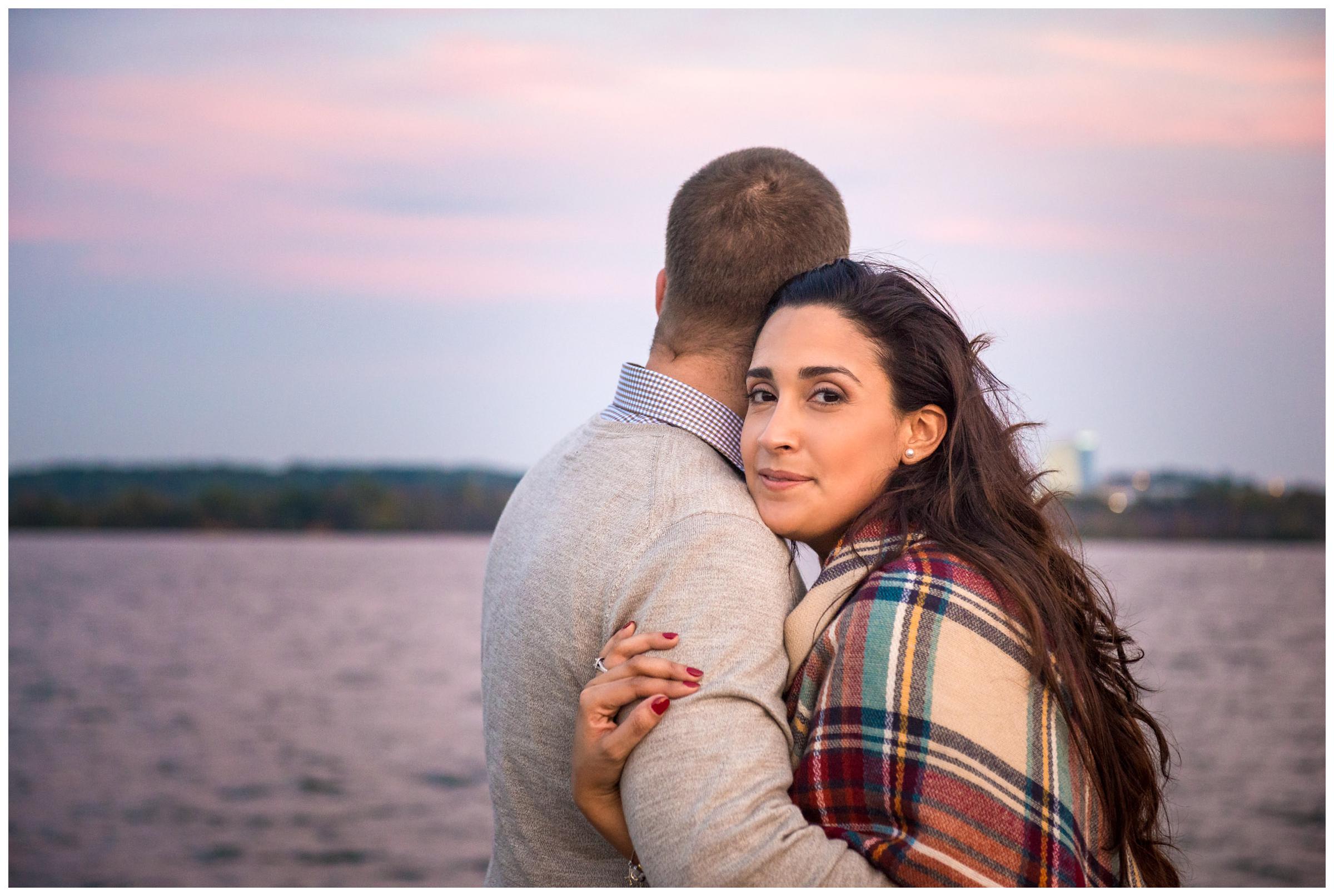 engaged couple embracing at sunset on Potomac River in Old Town Alexandria