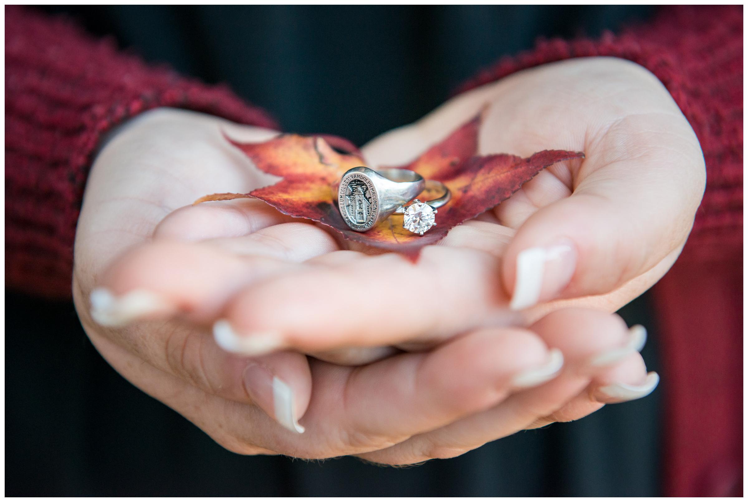 Bride-to-be holding engagement ring and Randolph-Macon class ring with fall leaves.