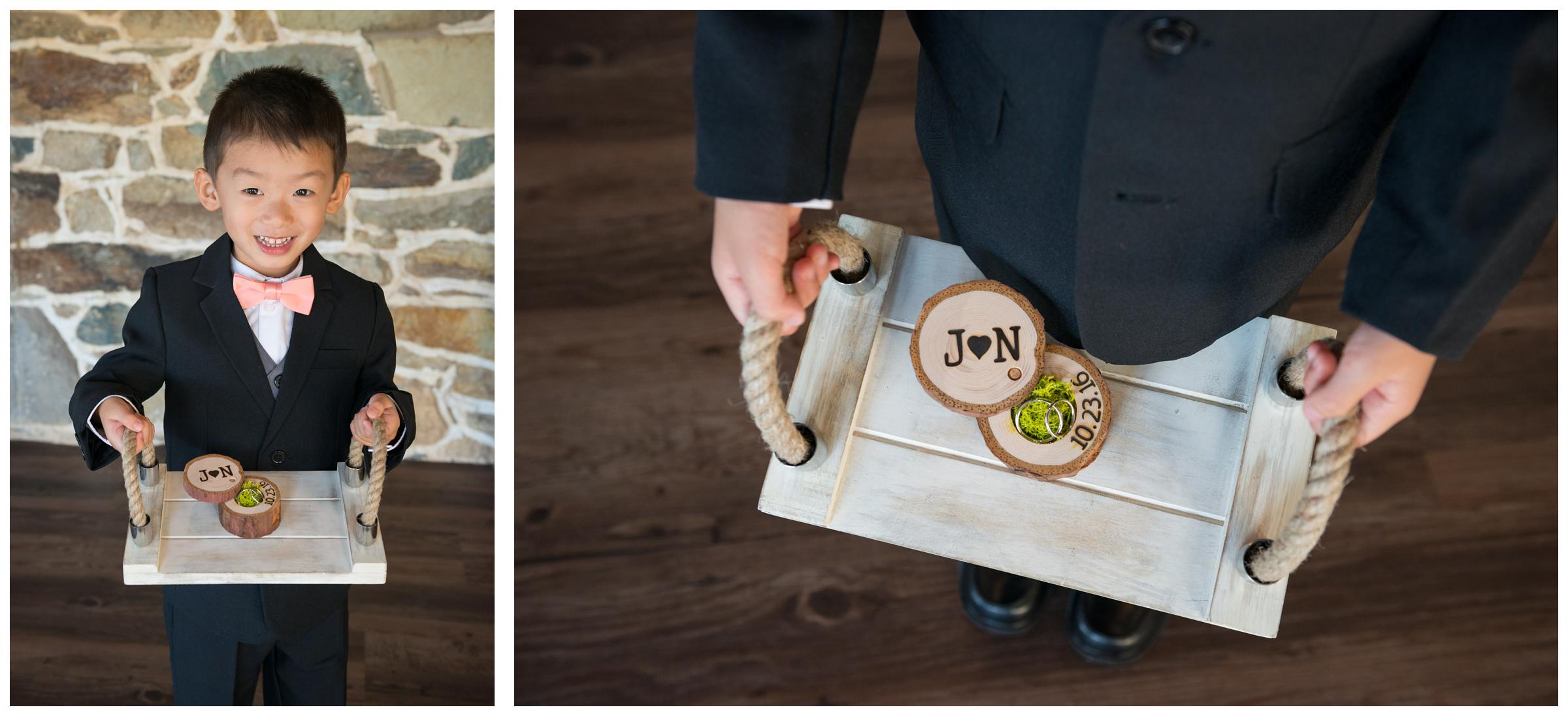 Ring bearer holding rustic wooden ring box on wooden tray.