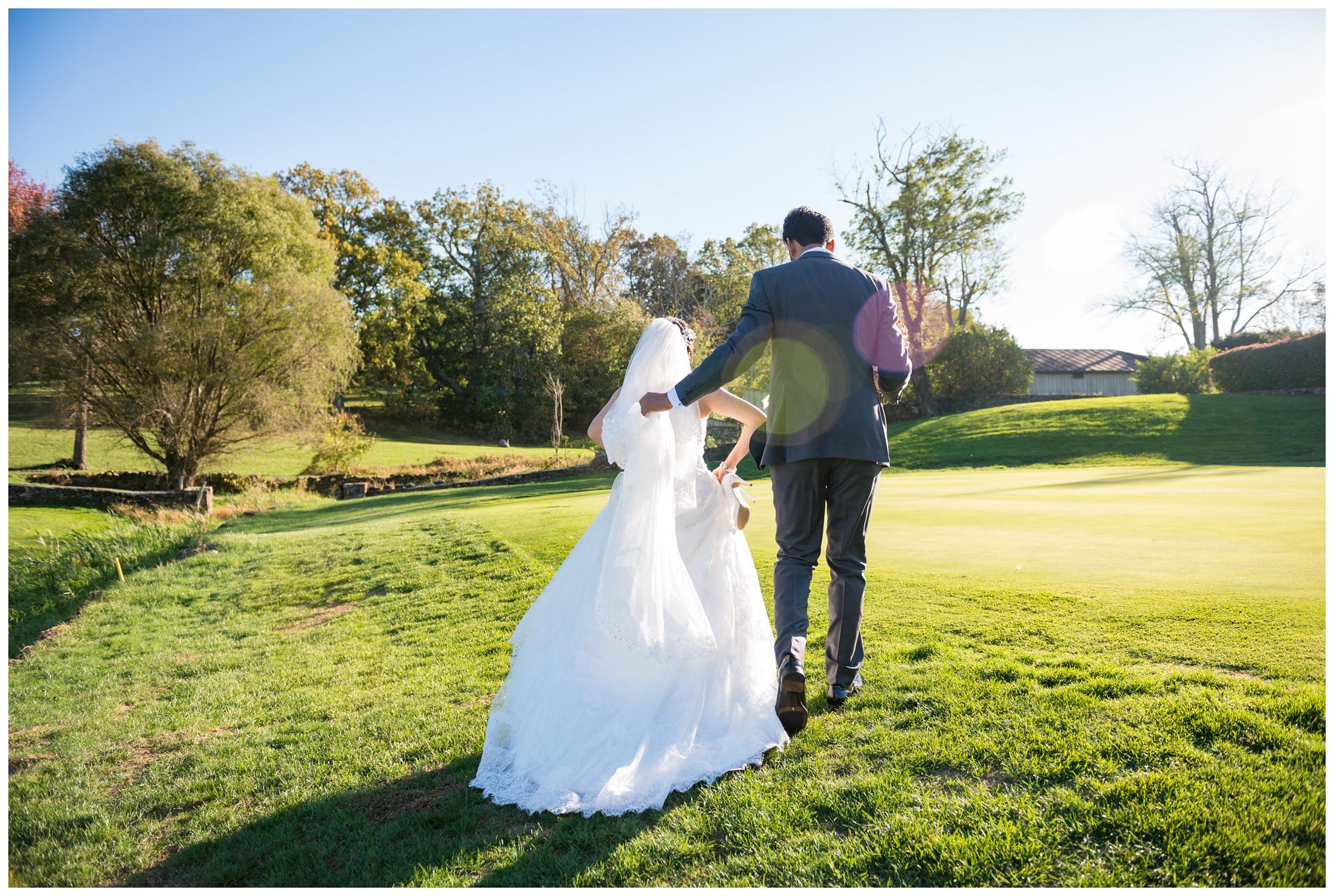 Groom helping bride up hillside at Stoneleigh Golf Club