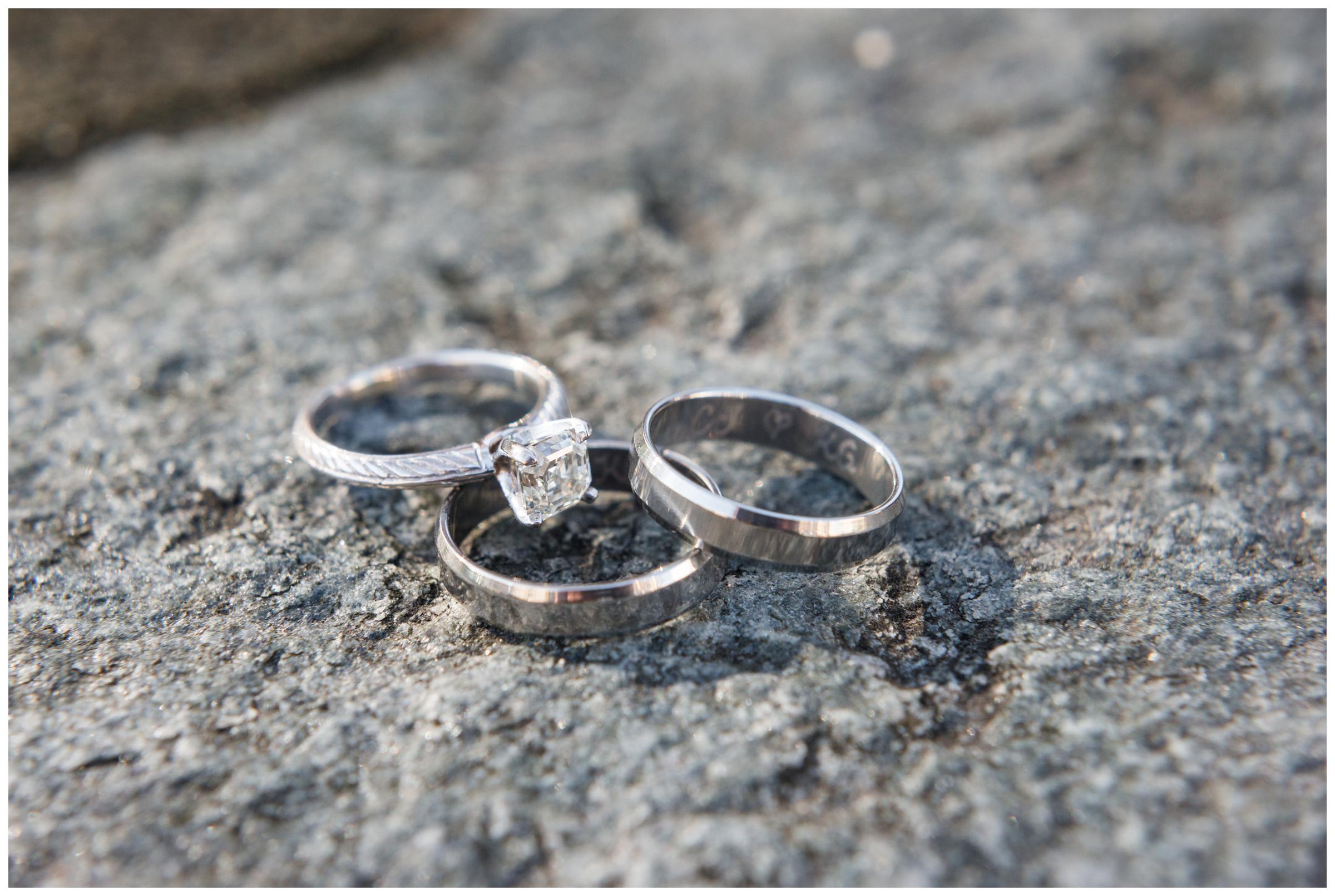 Engagement ring and engraved wedding rings on granite