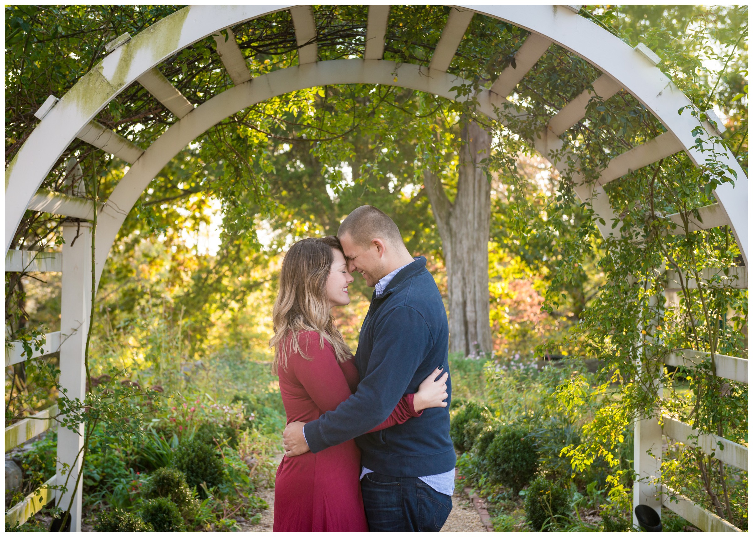 engaged couple under archway with fall foliage at Belmont in Fredericksburg, Virginia