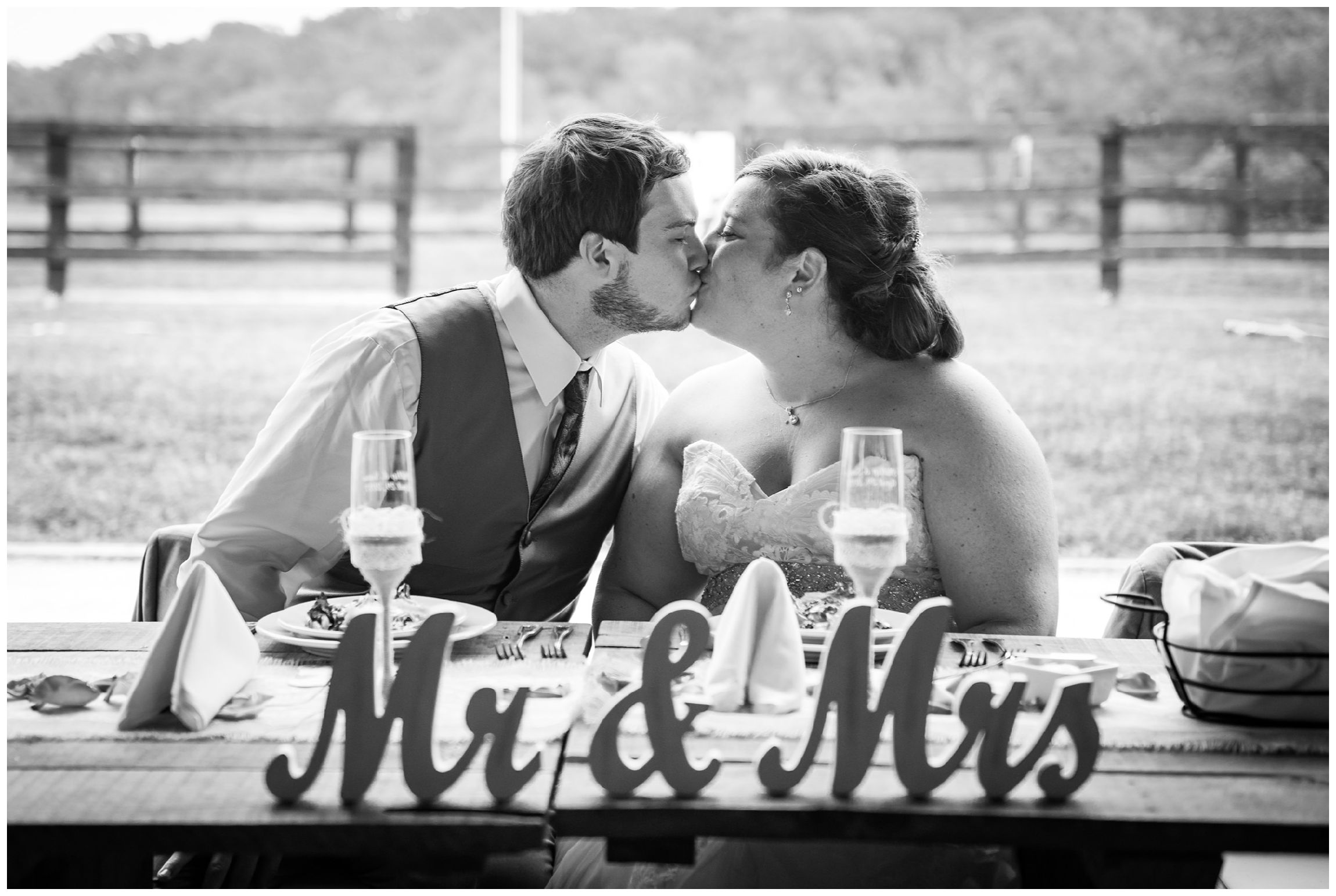 bride and groom kissing at head table during barn reception