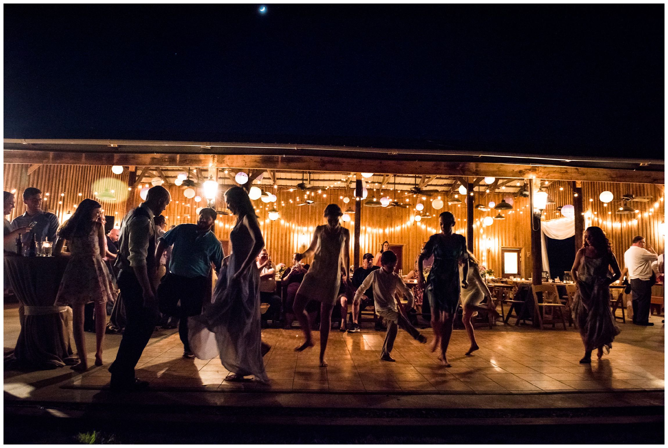 silhouettes of guests dancing at nighttime barn wedding reception