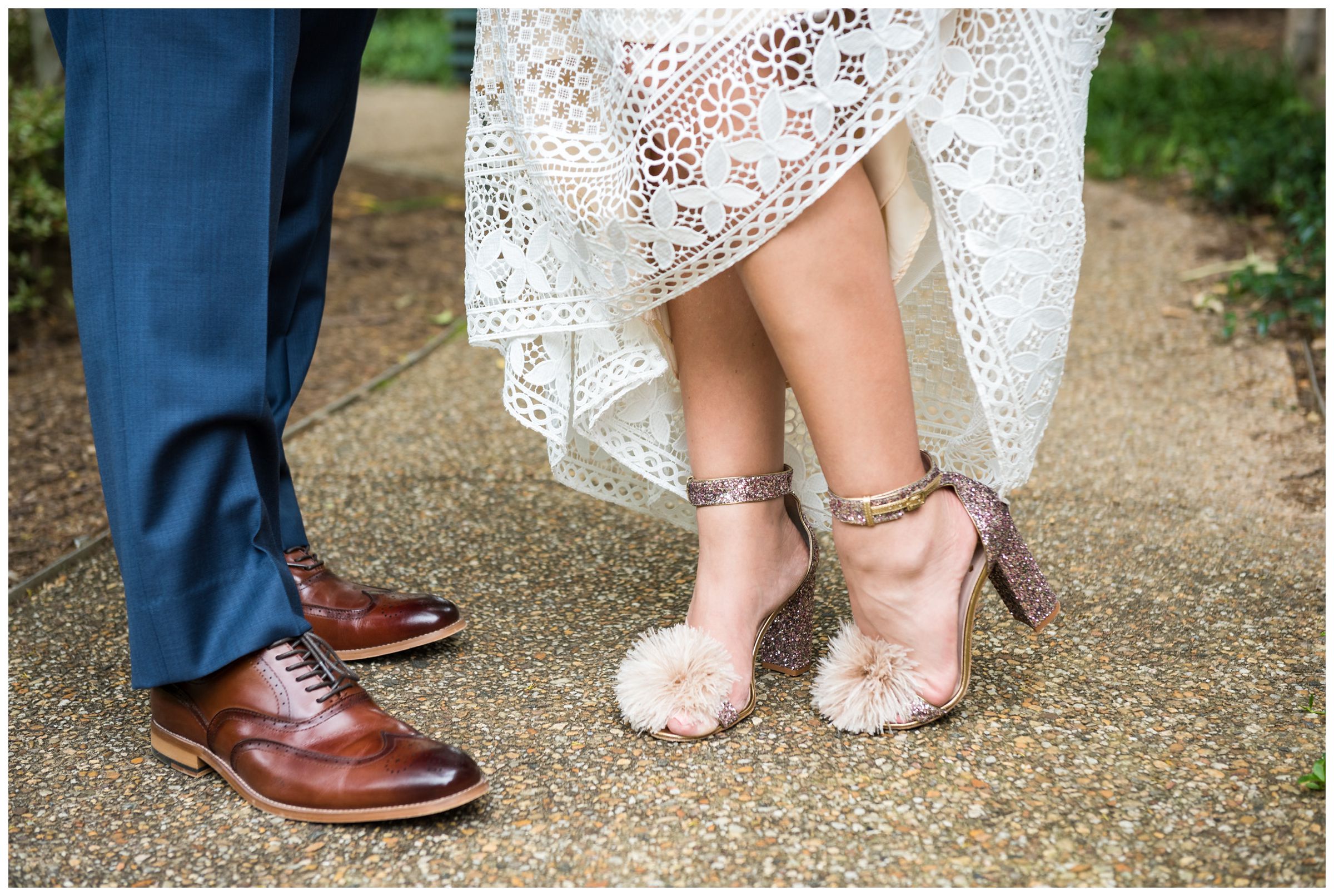 Detail photo of groom's navy Hilfiger suit and brown shoes and bride's BHLDN wedding dress and sparkly pom Kate Spade pink shoes