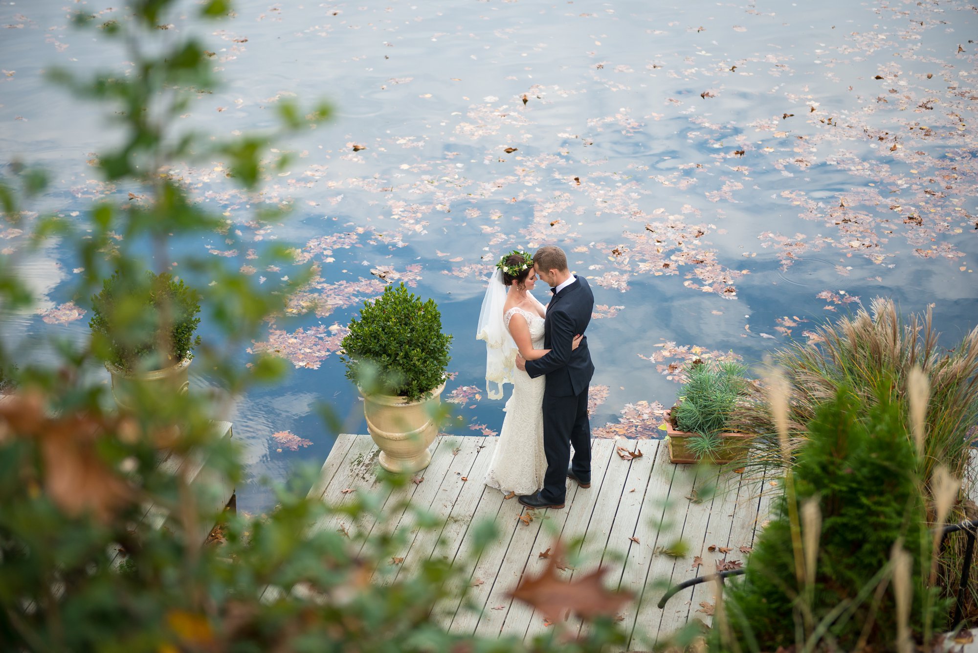 wedding photo by lake with leaves and greenery