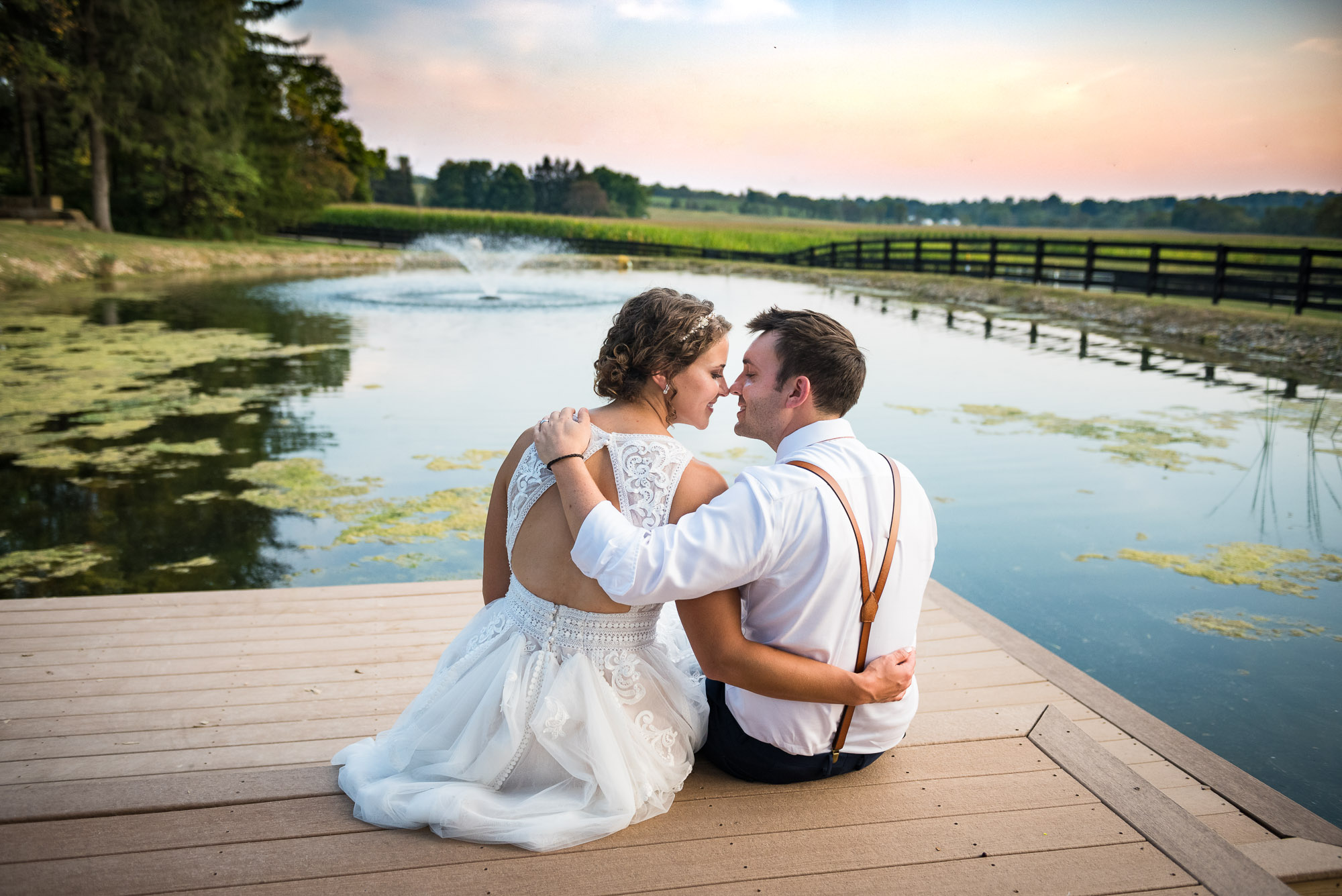 Lancaster Ohio wedding photography of bride and groom sitting by pond during farm wedding