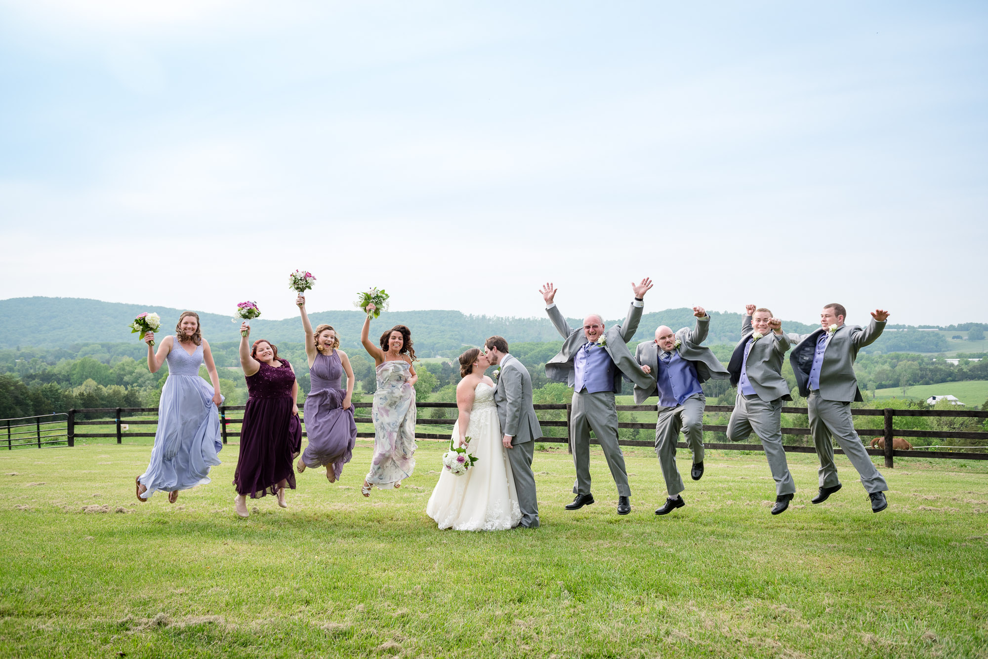 bridal party jumping into the air during rustic farm wedding