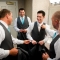 groomsmen helping groom get dressed before wedding