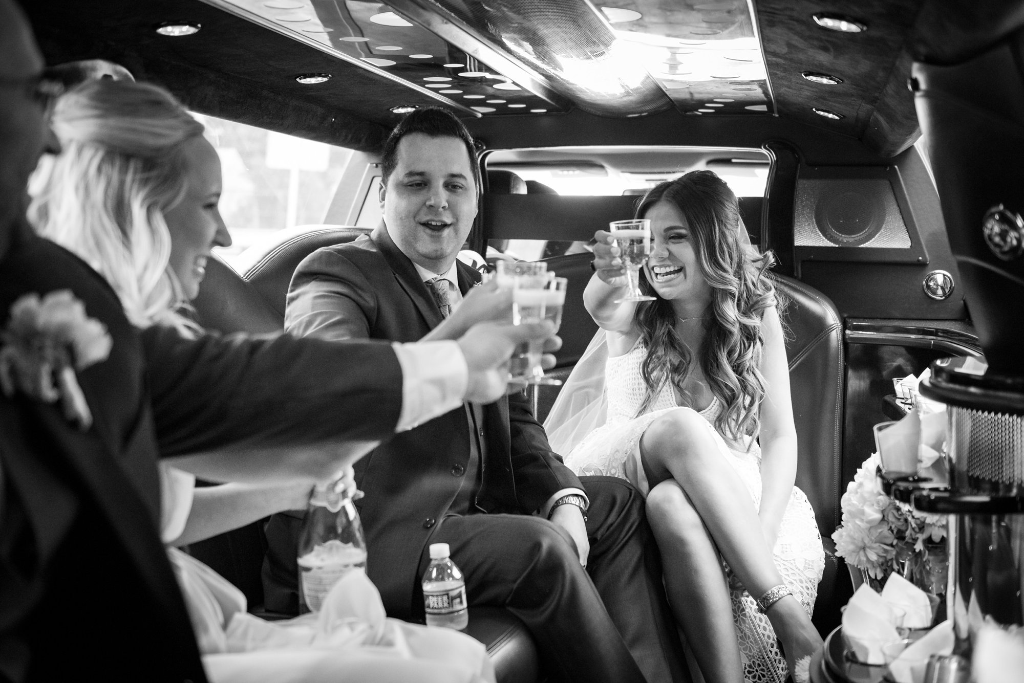 wedding party cheers in limo on the way to reception