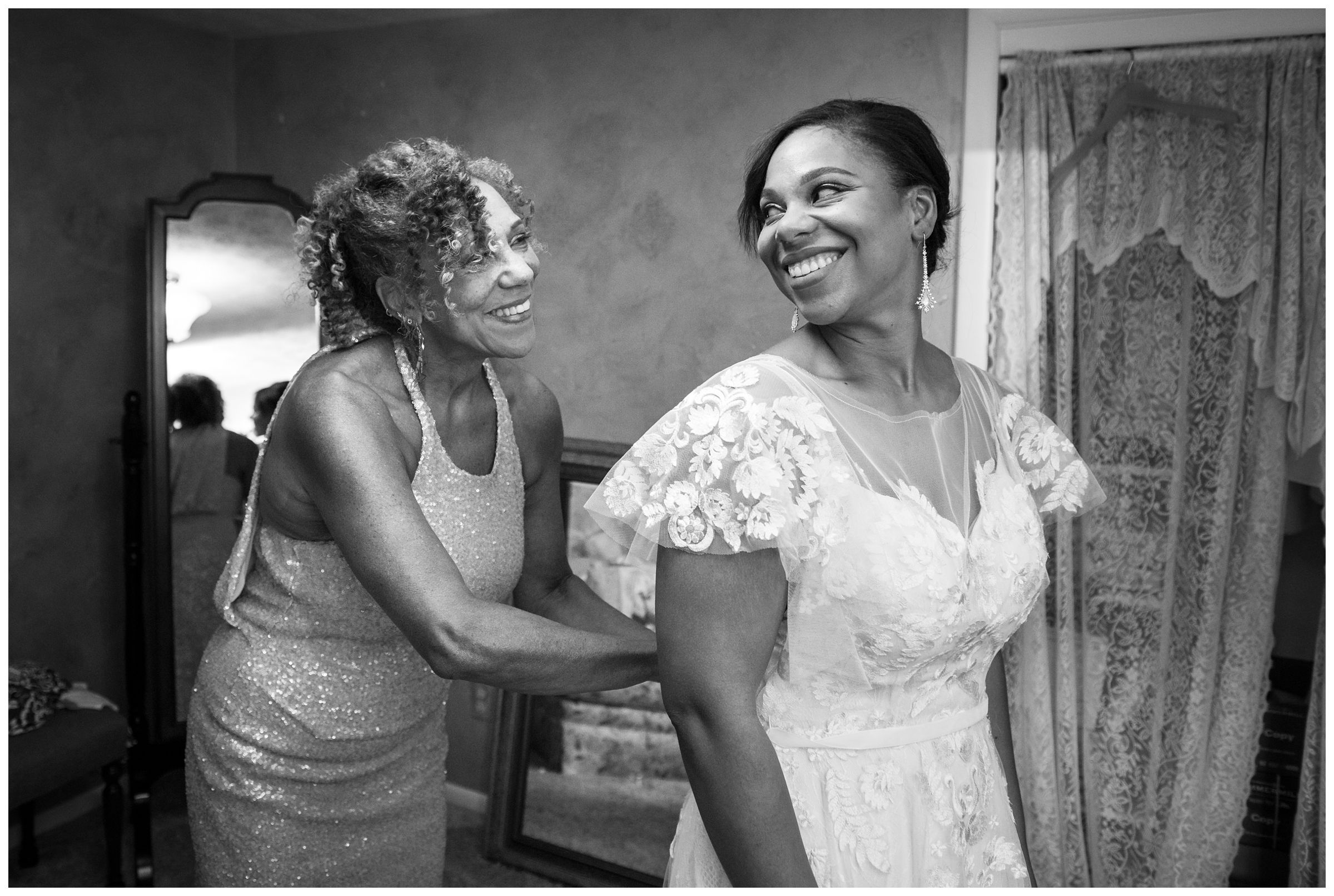 African American mom helping bride daughter into gown before Columbus Ohio wedding at Jorgensen Farms Historic Barn