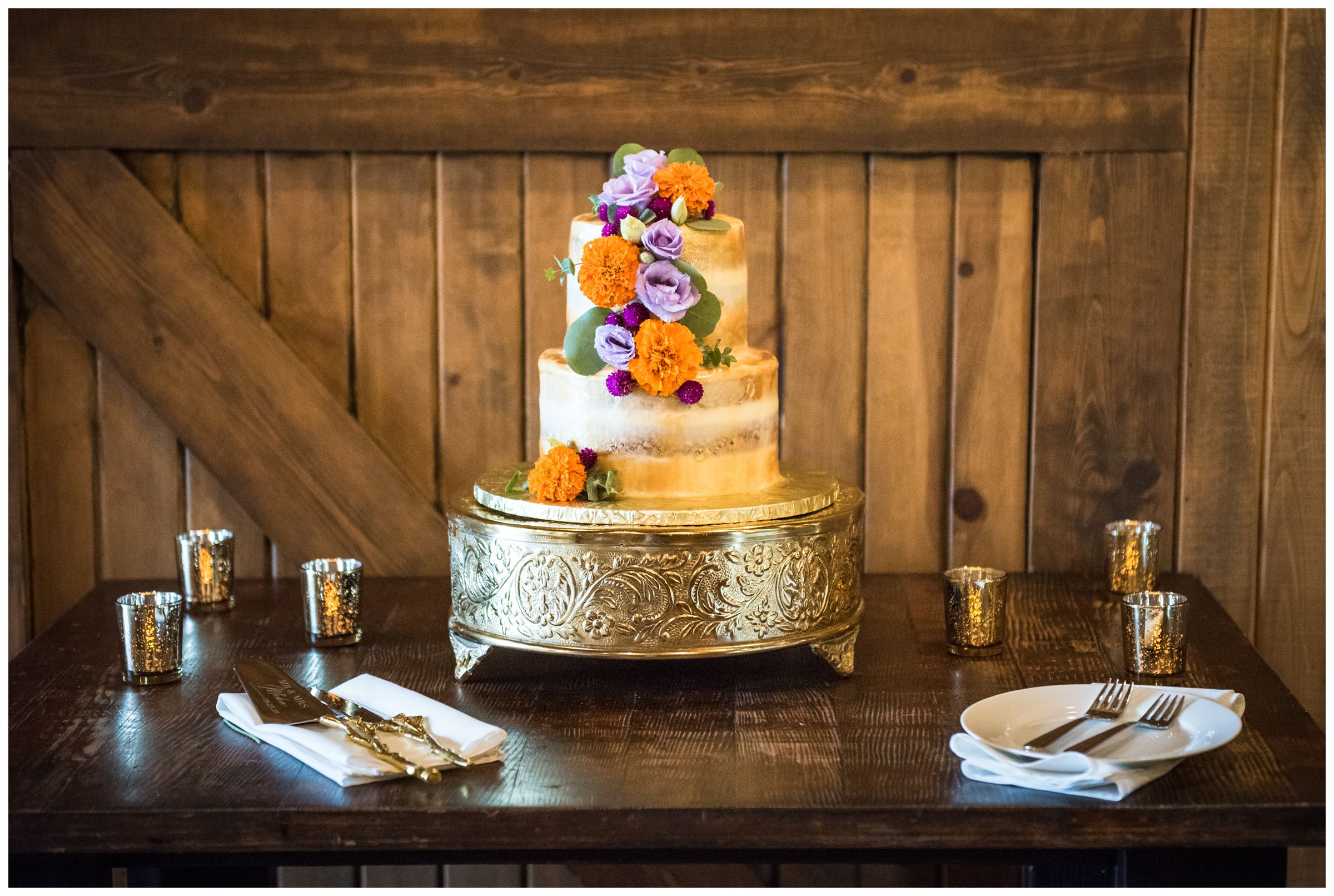 gold wedding cake with orange and purple flowers including Indian wedding flower marigolds