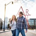 engaged couple laughing in front of Art sculpture in downtown Columbus