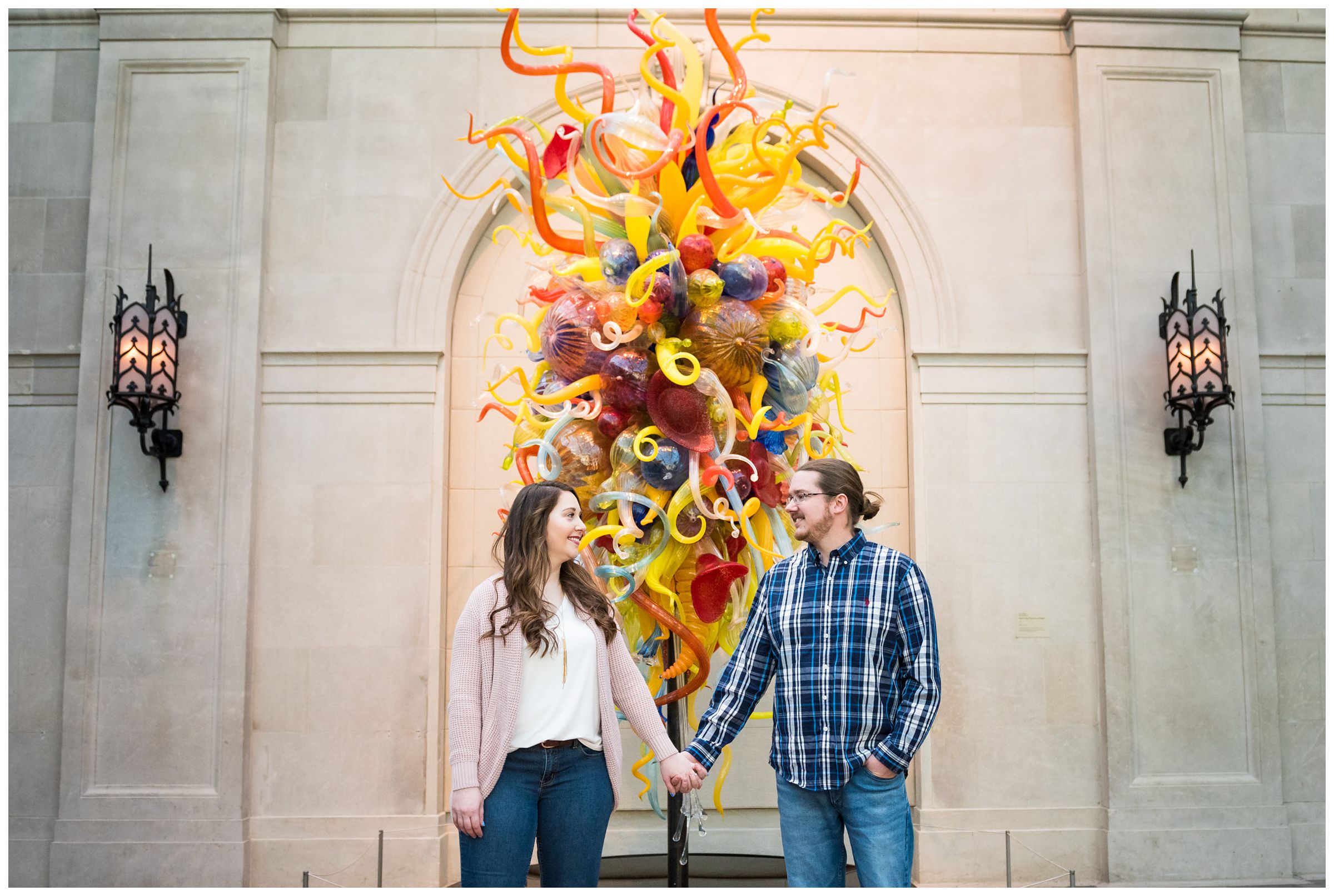 Engaged couple holding hands in front of a Chihuly glass sculpture at the Columbus Museum of Art in Ohio