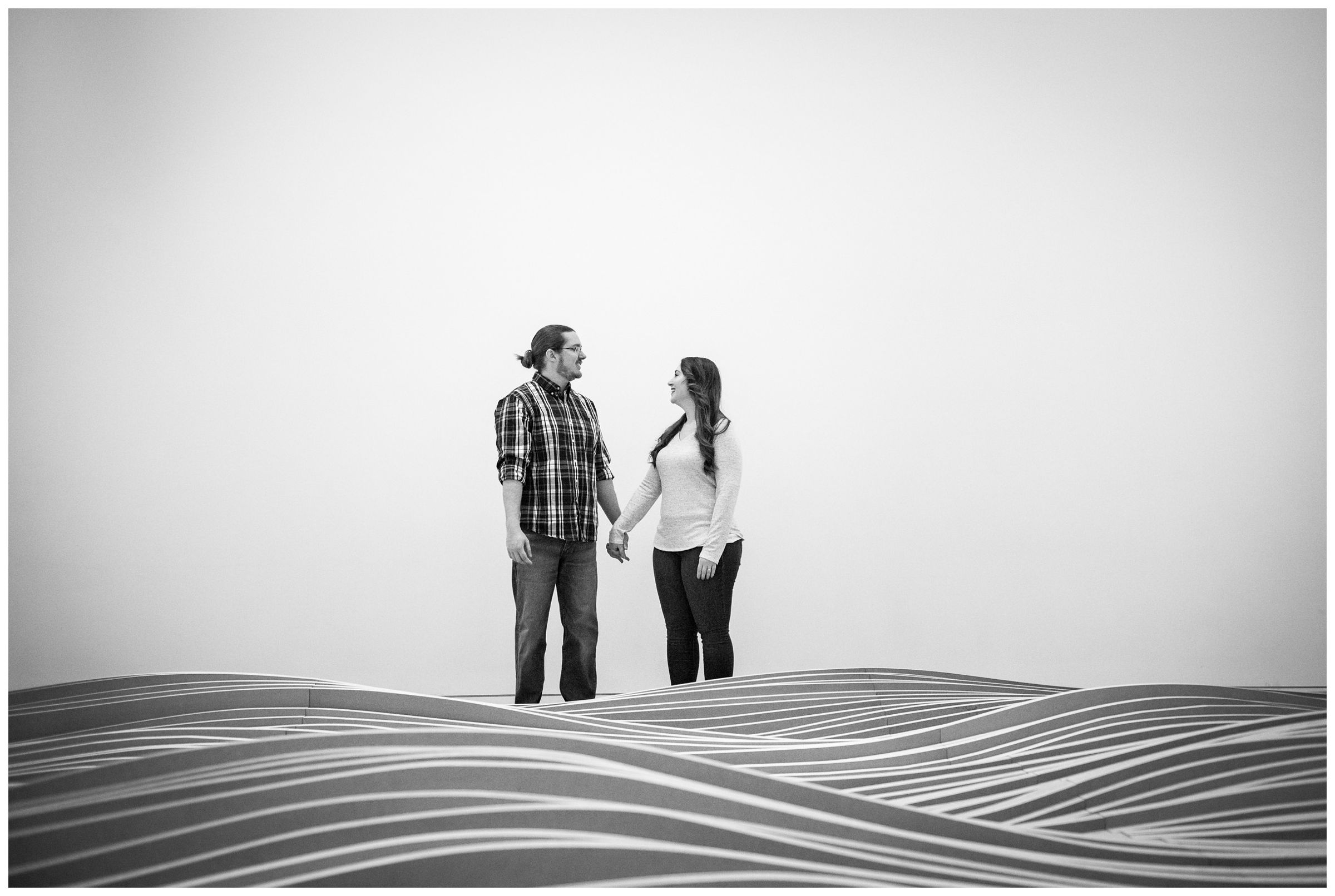 engaged couple standing behind wavy wood sculpture at the Columbus Museum of Art