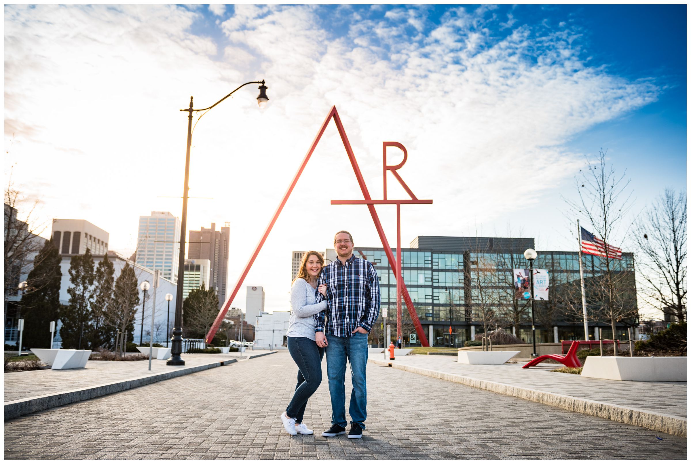 engaged couple photographed in front of Art sculpture in downtown Columbus by Ohio wedding photographer