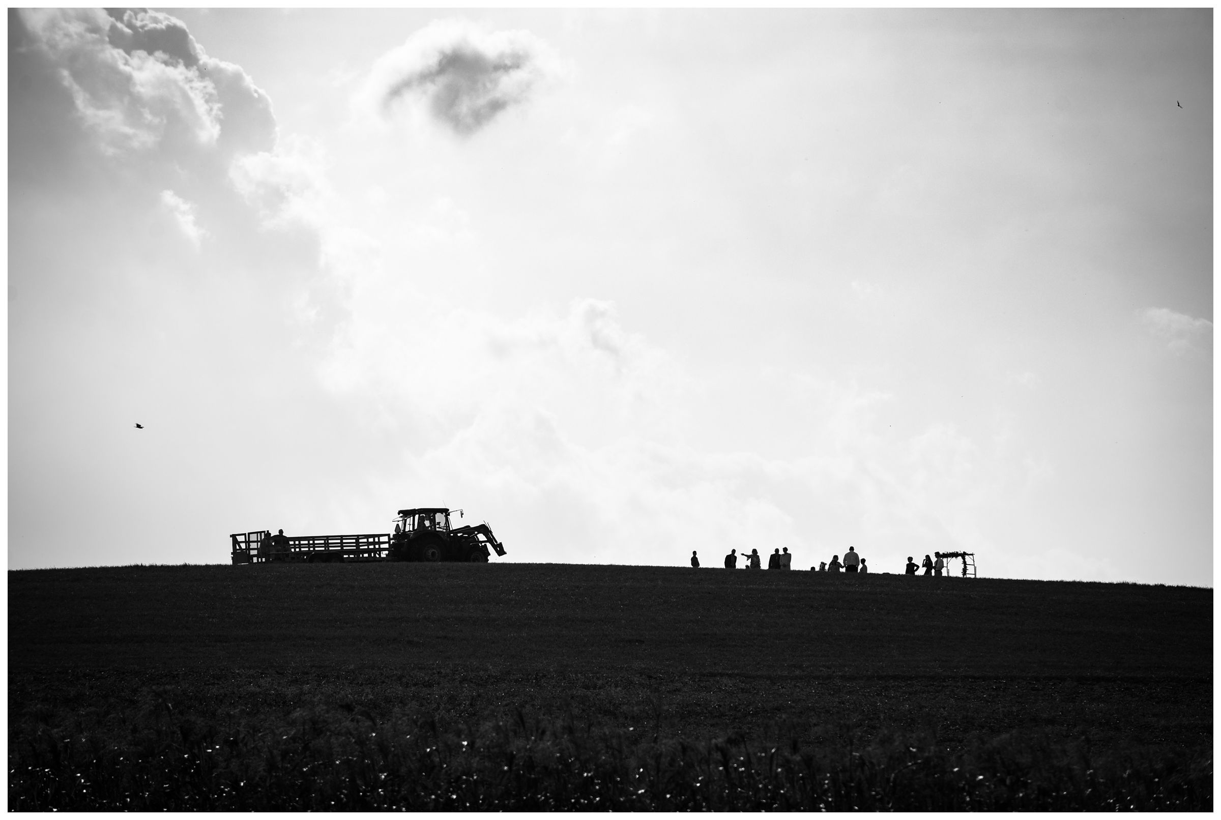 Silhouette of a hilltop wedding ceremony with tractor wagon