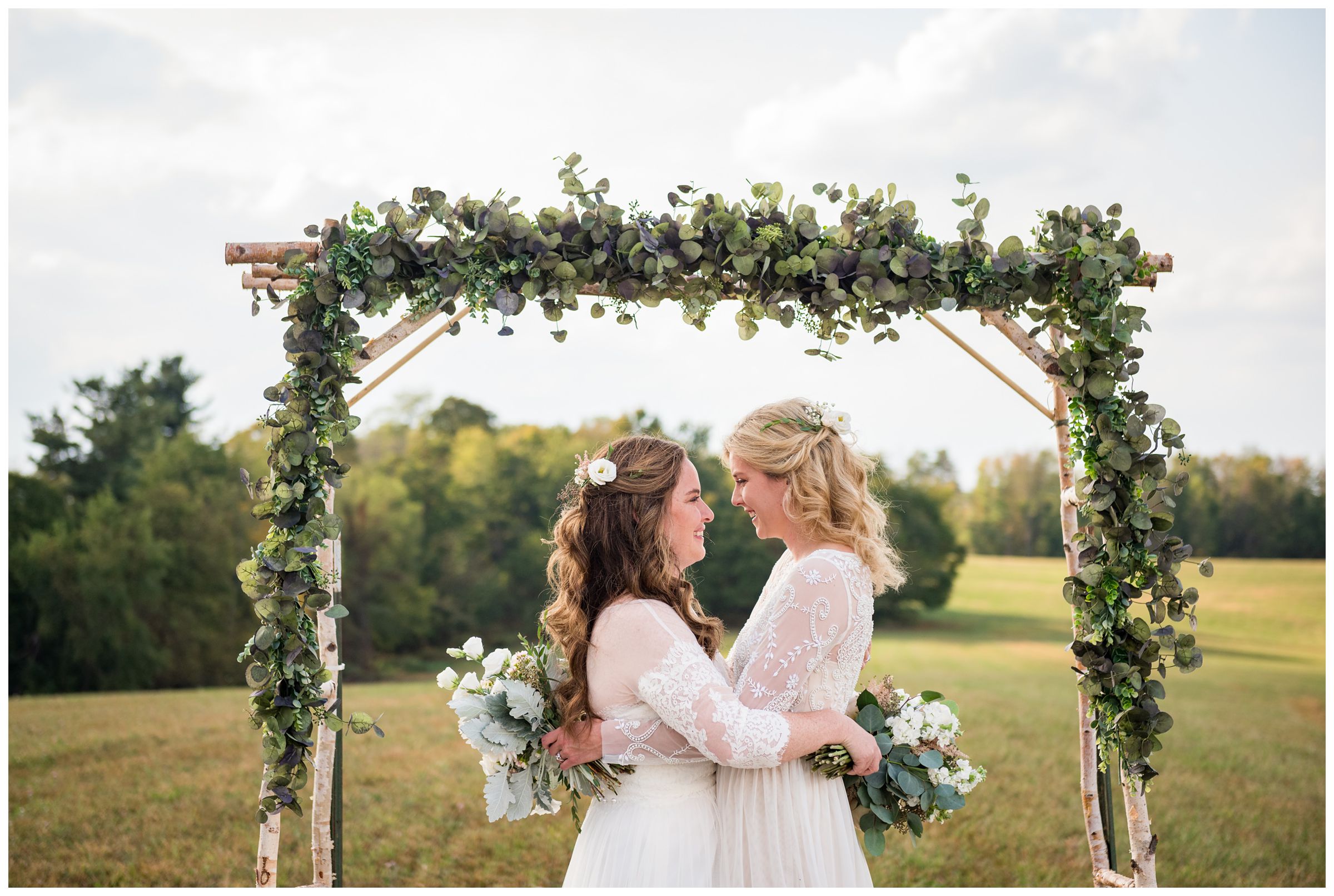 Lesbian couple bridal portraits under greenery arch