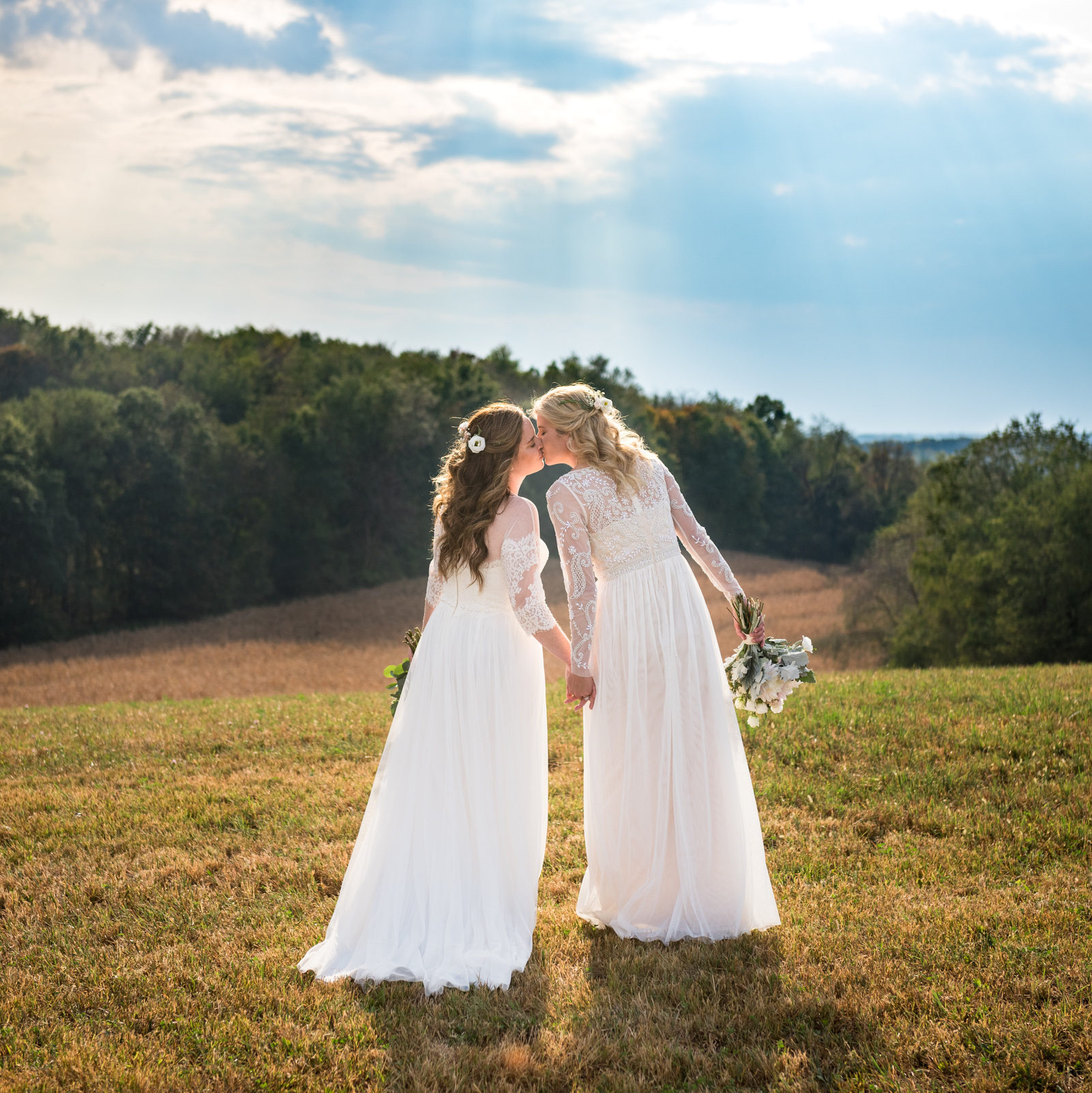 Two brides kissing on hilltop during same-sex lesbian wedding in central Ohio.